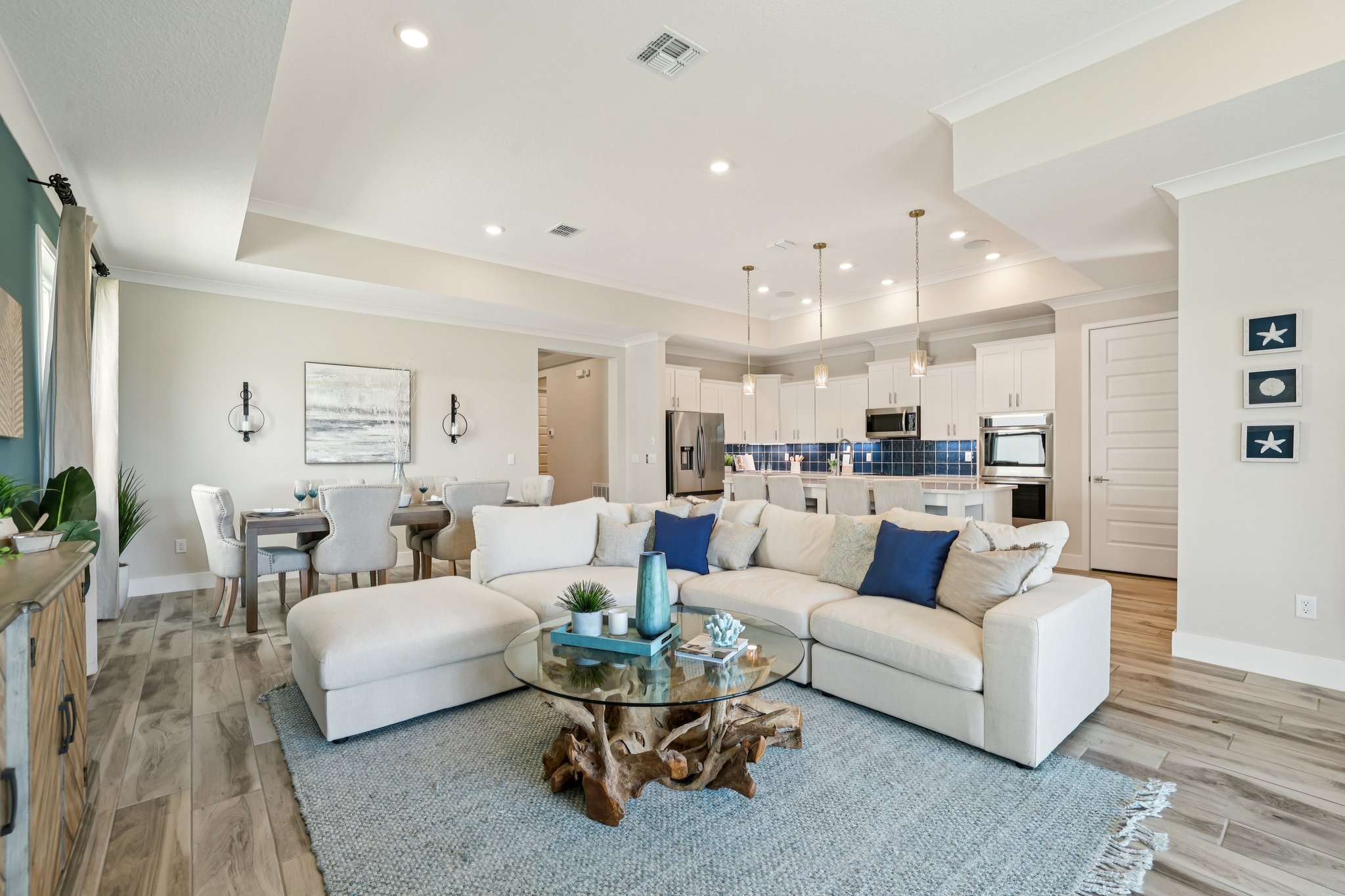 Spacious modern open-concept living room and kitchen with a light beige sectional sofa, rustic coffee table, and elegant dining area.