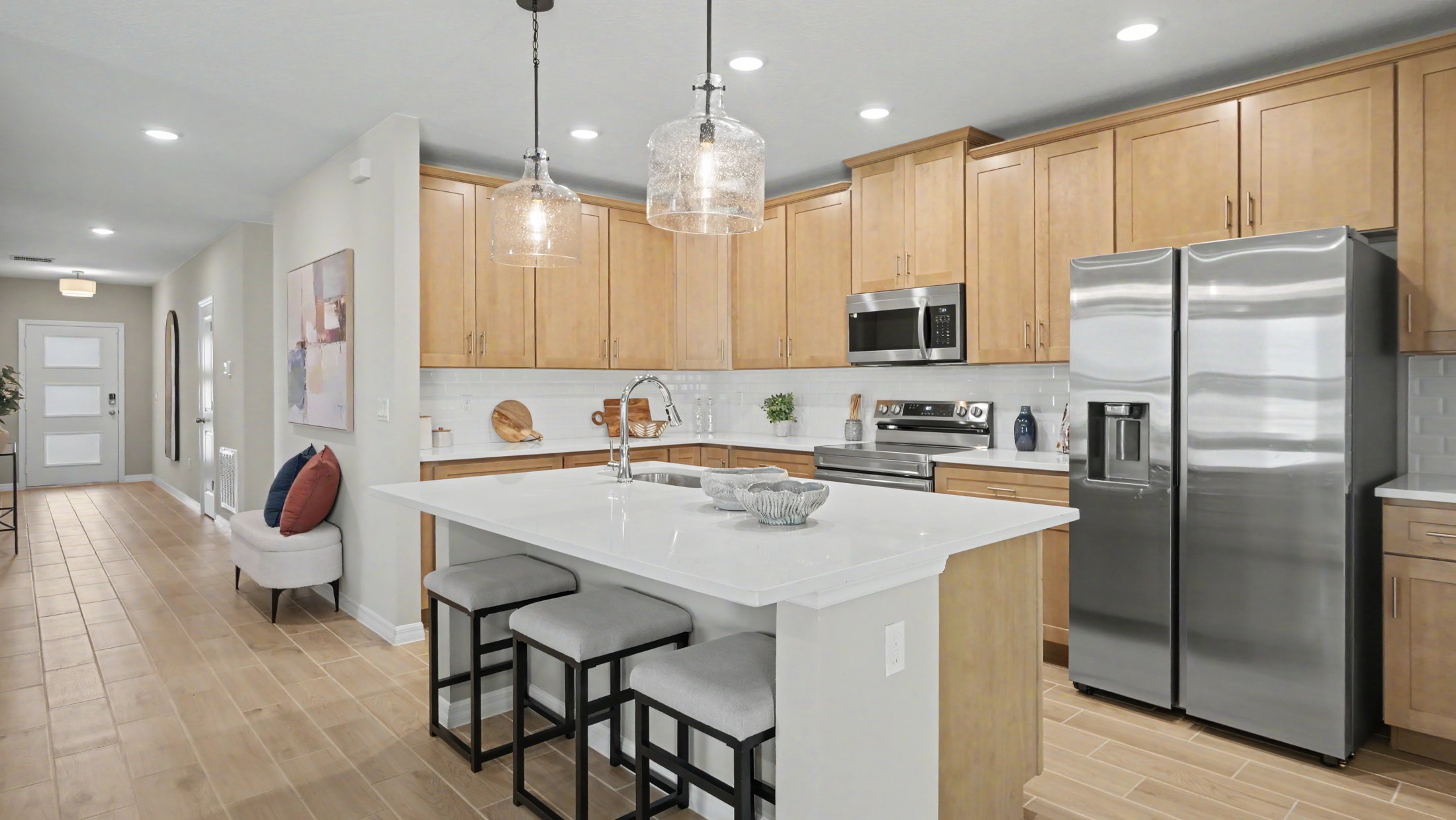 Modern kitchen featuring wood cabinetry, stainless steel appliances, a large island with seating, and pendant lighting.