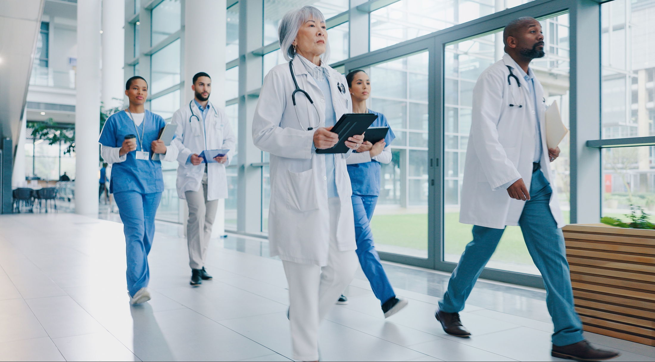 A diverse group of healthcare professionals walking through a modern hospital corridor.