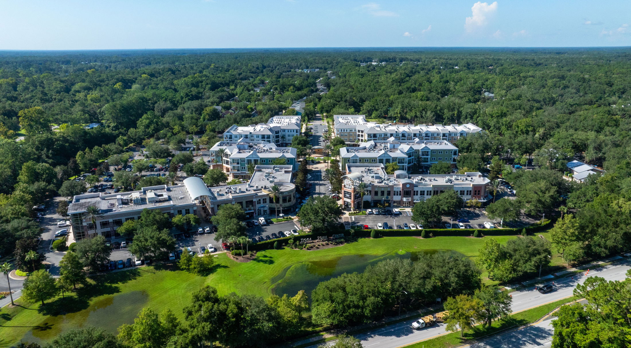 Aerial view of a modern town center surrounded by lush greenery and residential buildings.