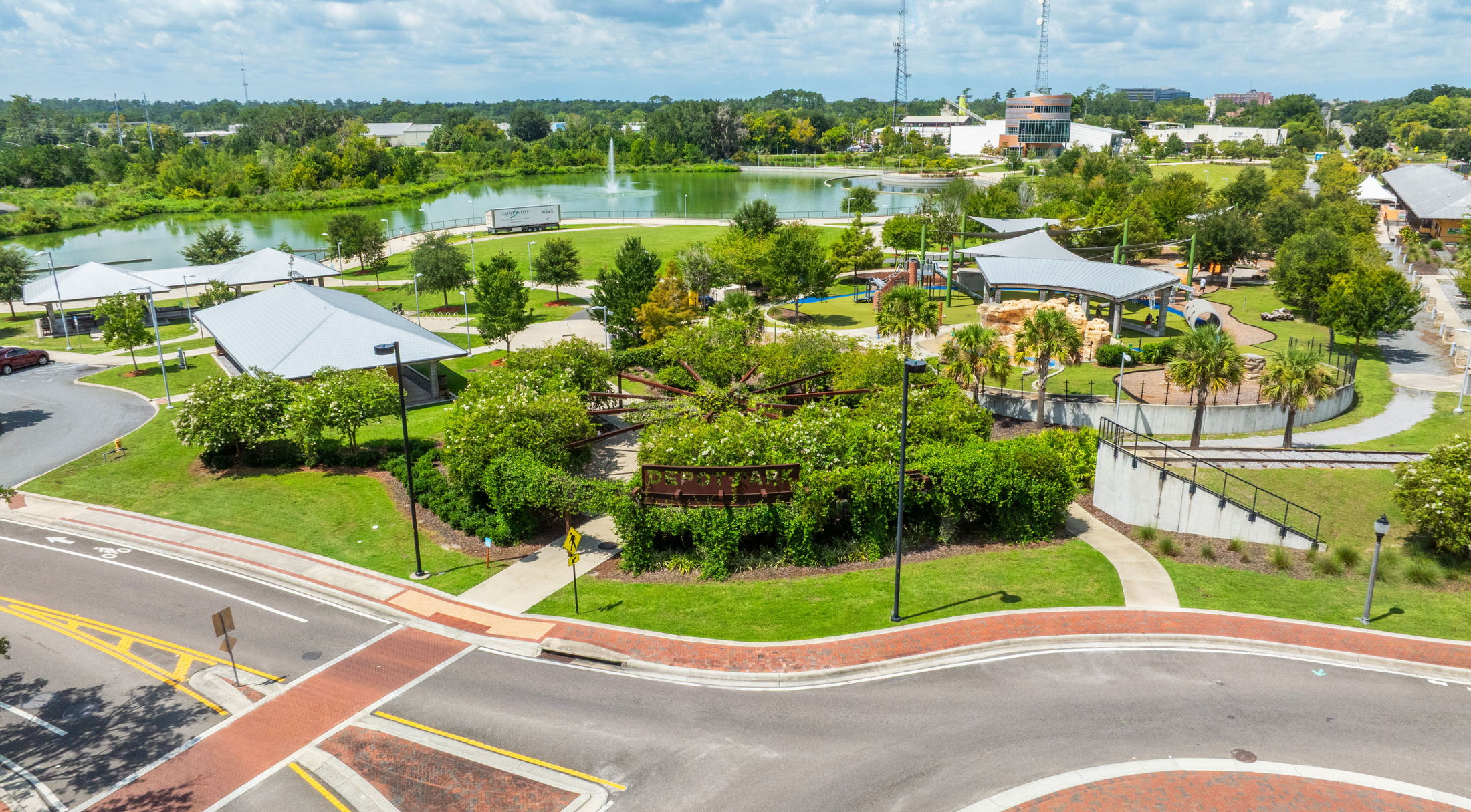 Aerial view of Depot Park showcasing green spaces, playgrounds, and a serene lake in Gainesville, Florida.
