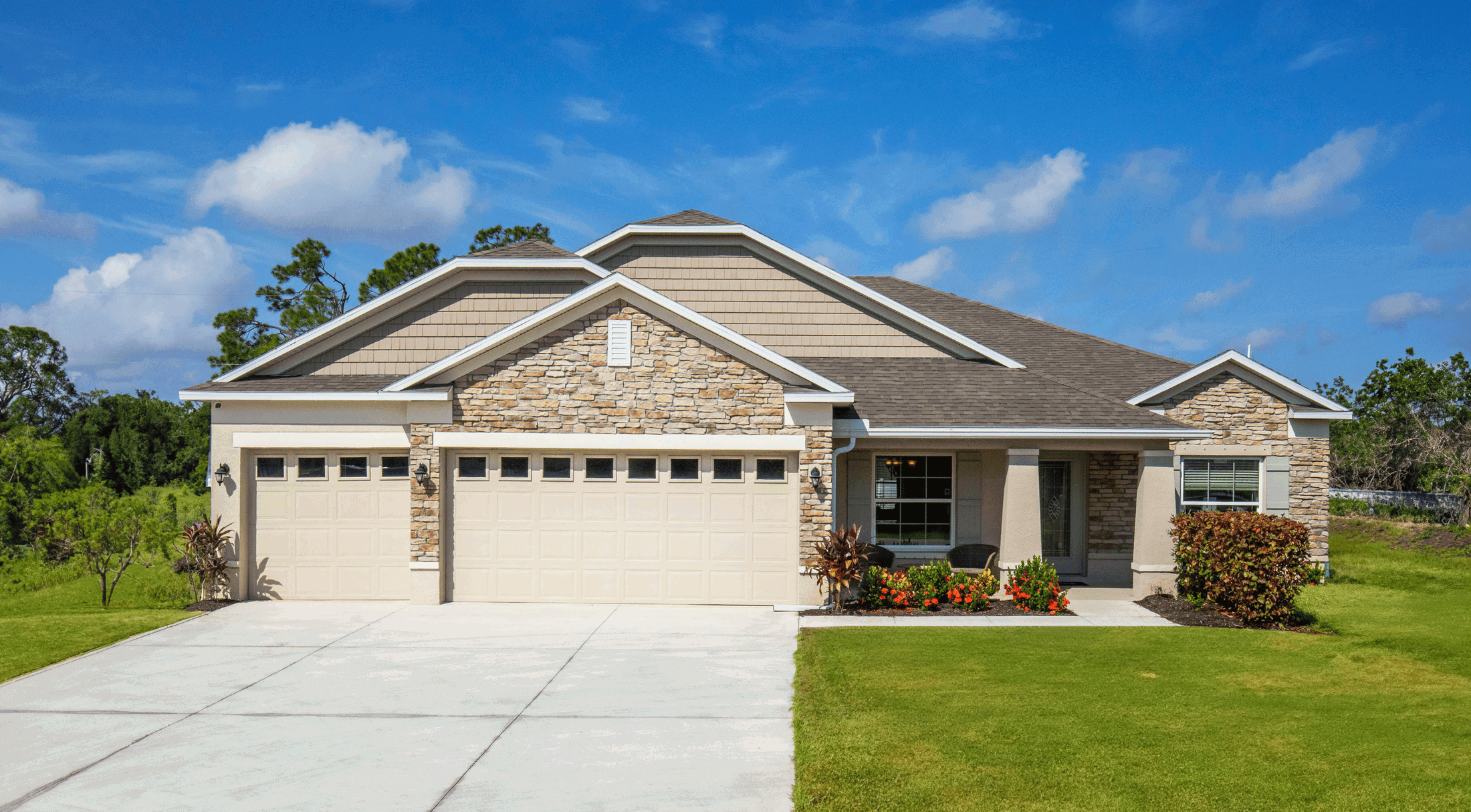 Modern single-story suburban house with stone veneer facade, three-car garage, and well-maintained lawn.