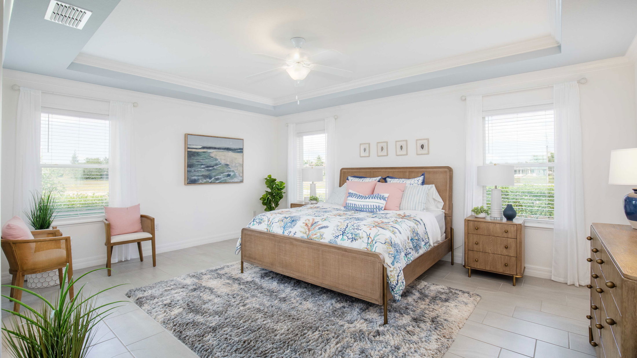 Bright and airy bedroom with wicker furniture, coral-themed bedding, and coastal decor accents.