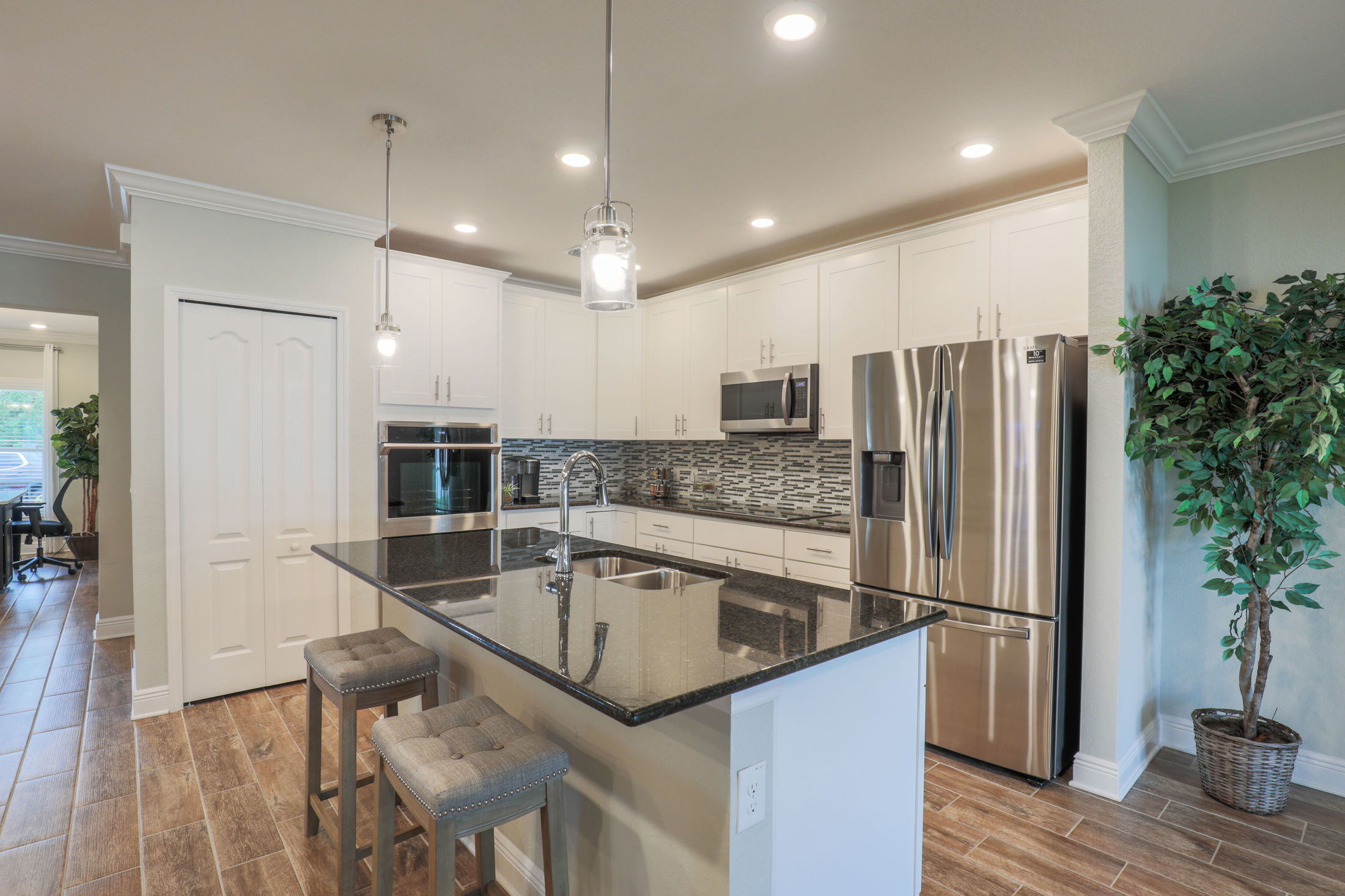 Modern kitchen with white cabinets, stainless steel appliances, granite countertops, and a center island with seating.
