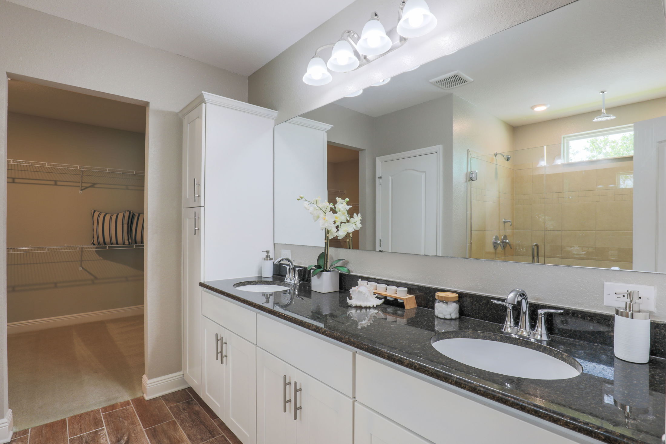 Spacious modern bathroom with dual sinks, granite countertops, and glass shower enclosure.