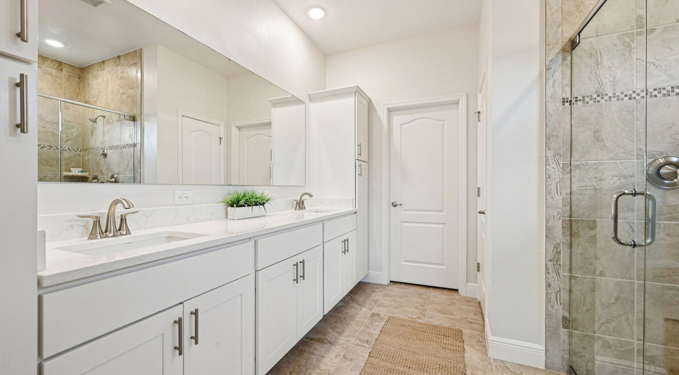 Modern bathroom with white cabinetry, large mirror, and a glass-enclosed shower.