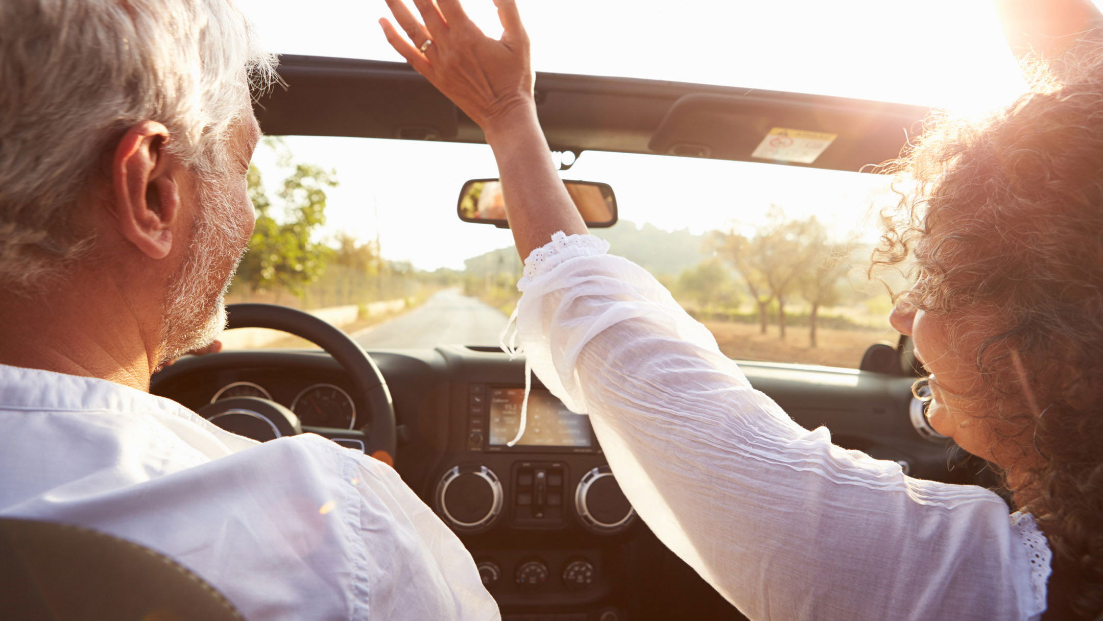 mature couple riding in a convertible into the sunset in naples, fl