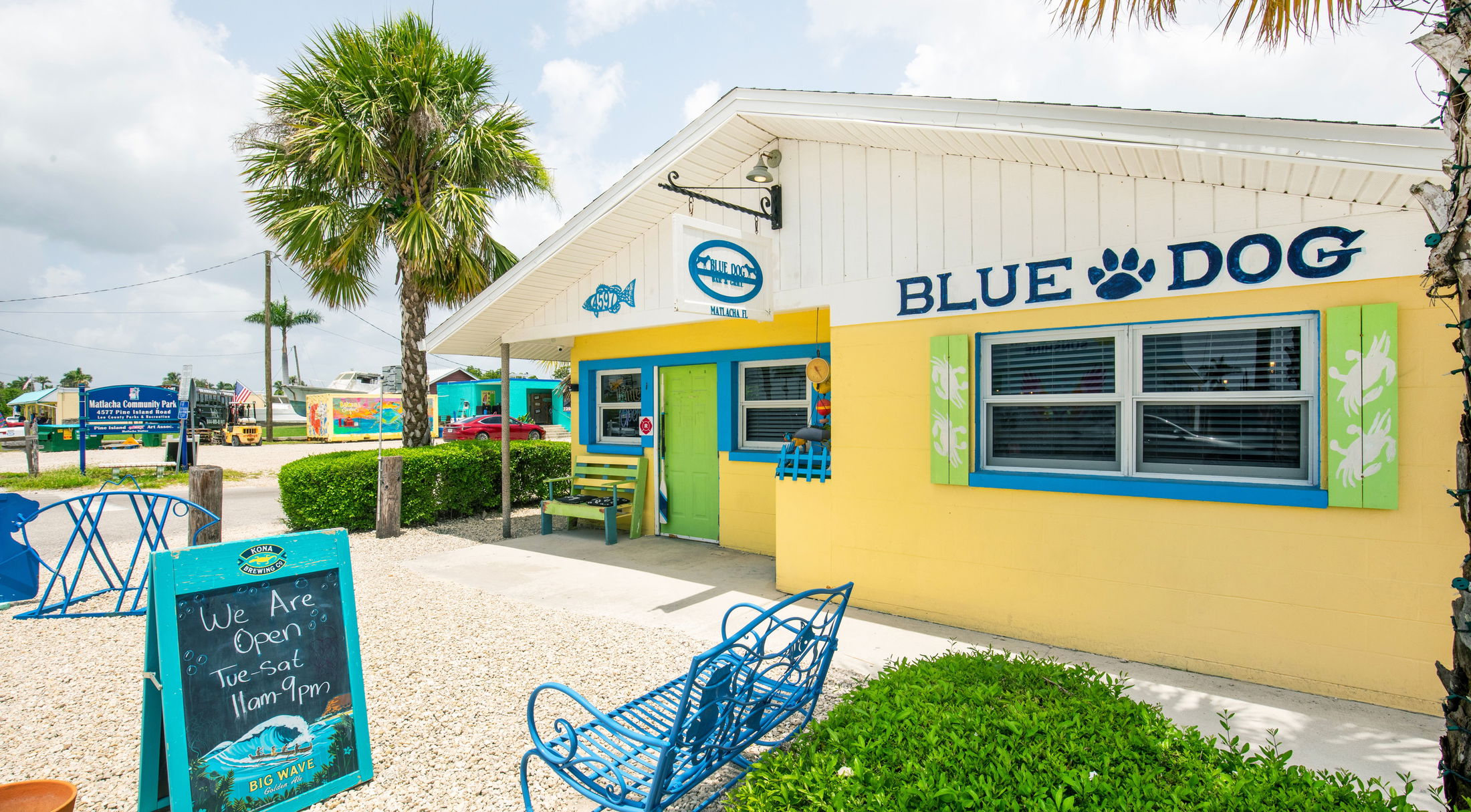 Bright and colorful exterior of Blue Dog Bar & Grill in Matlacha, Florida, featuring vibrant signage and a welcoming outdoor seating area.