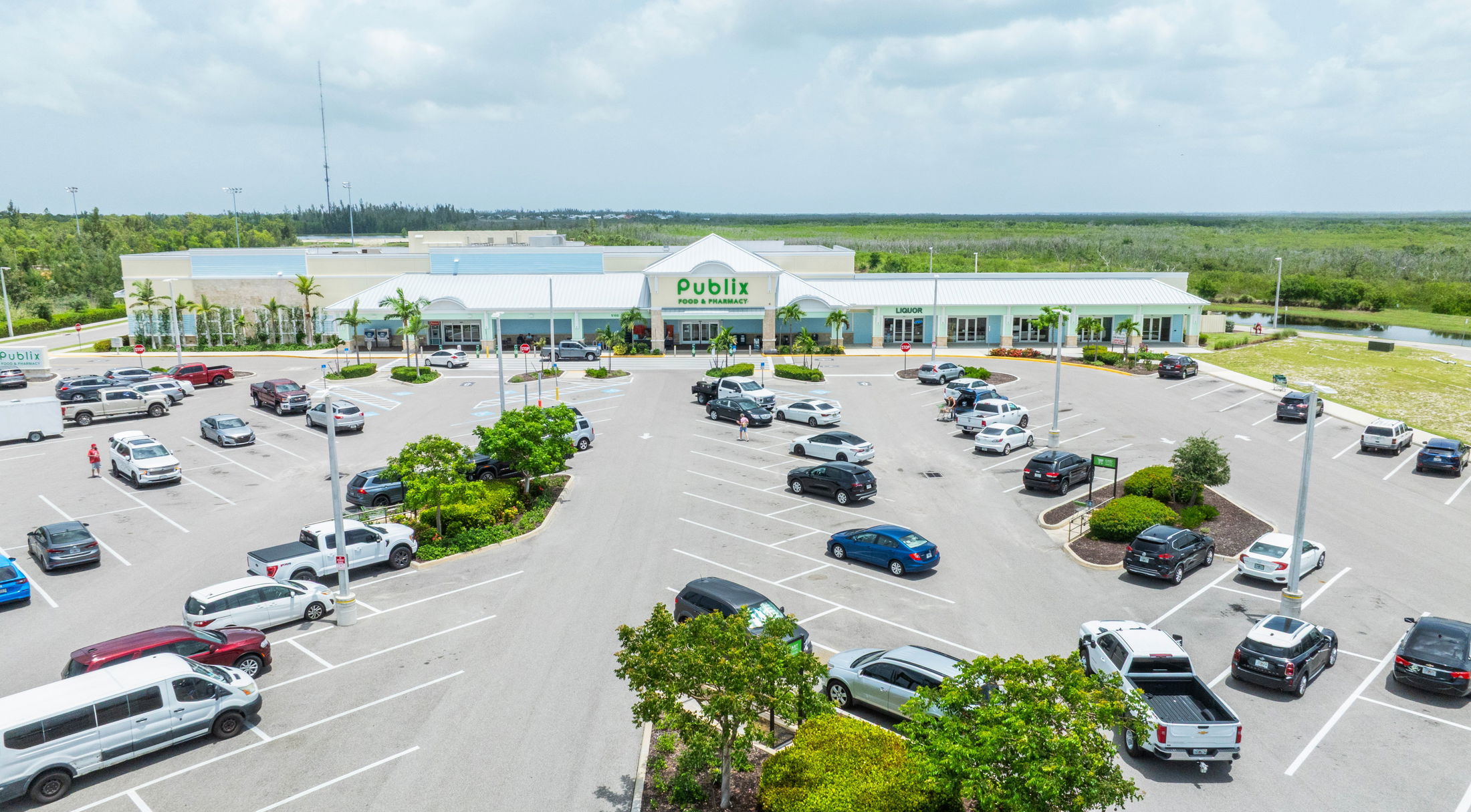 Aerial view of a Publix supermarket with a parking lot filled with cars on a sunny day.