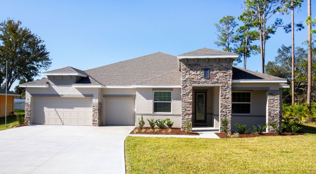 Modern single-story home with stone façade, three-car garage, and manicured lawn under a clear blue sky.