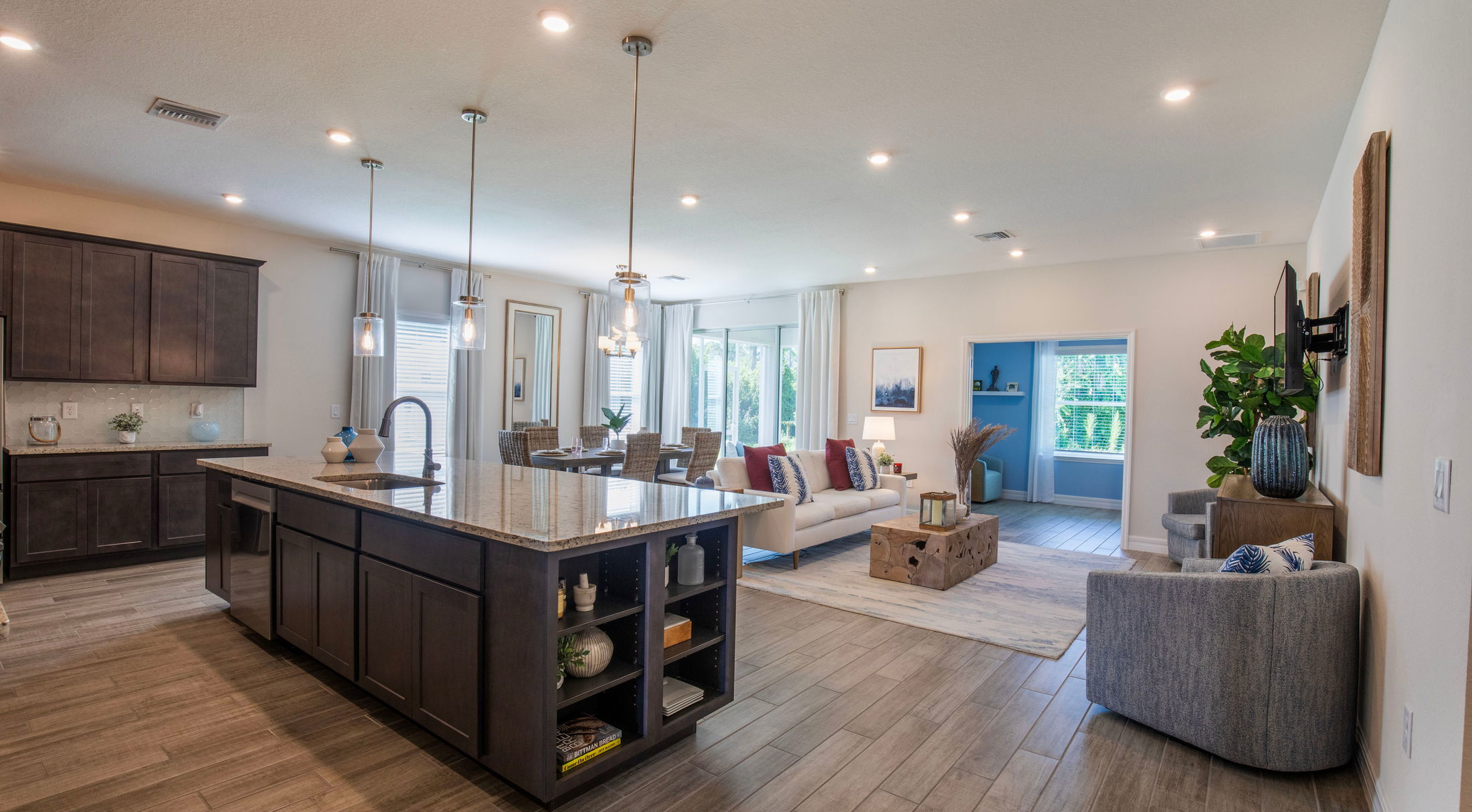Modern open-concept kitchen and living room with dark wood cabinets, large island, and elegant decor.