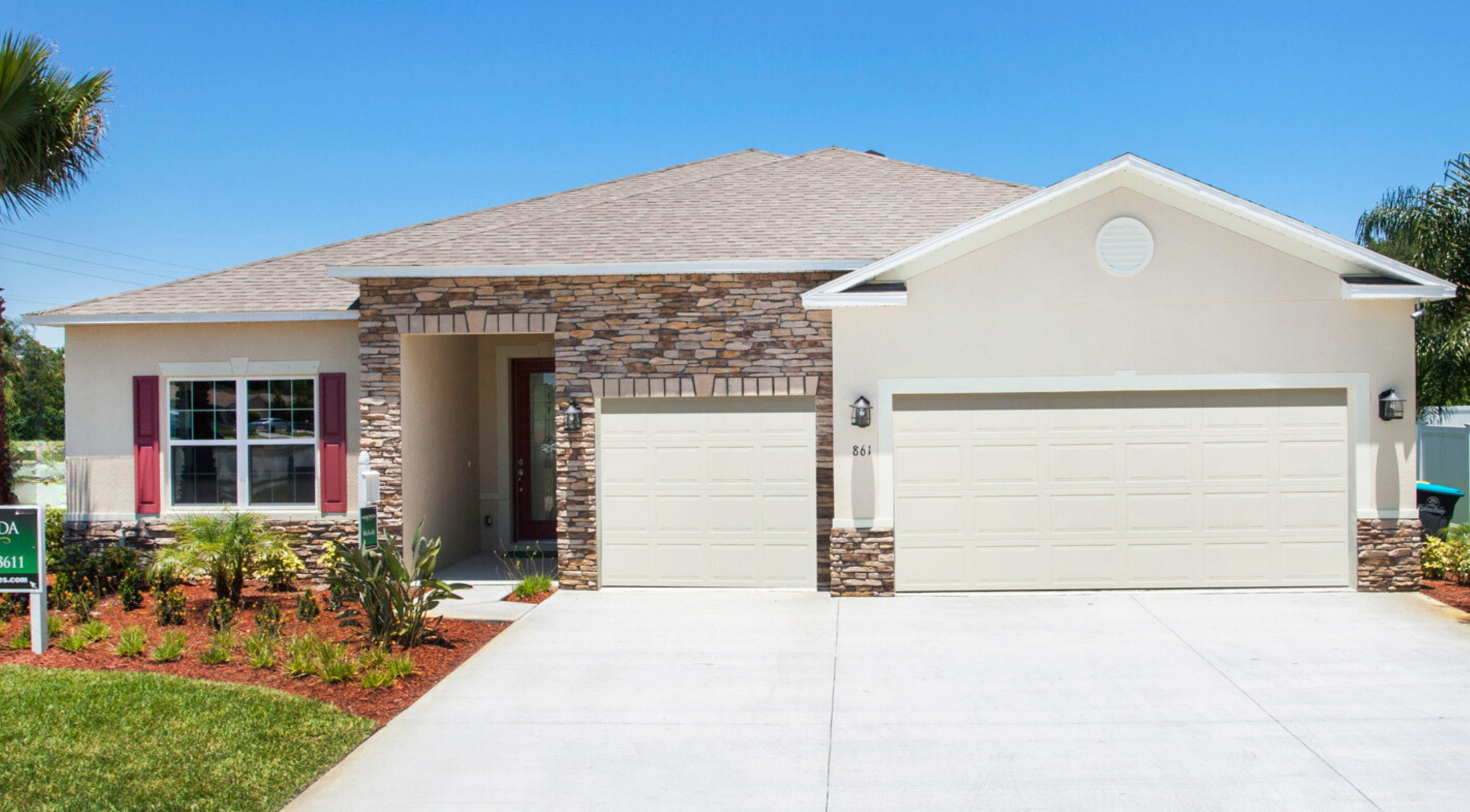 Modern single-story house with stone facade, two-car garage, and landscaped front yard.