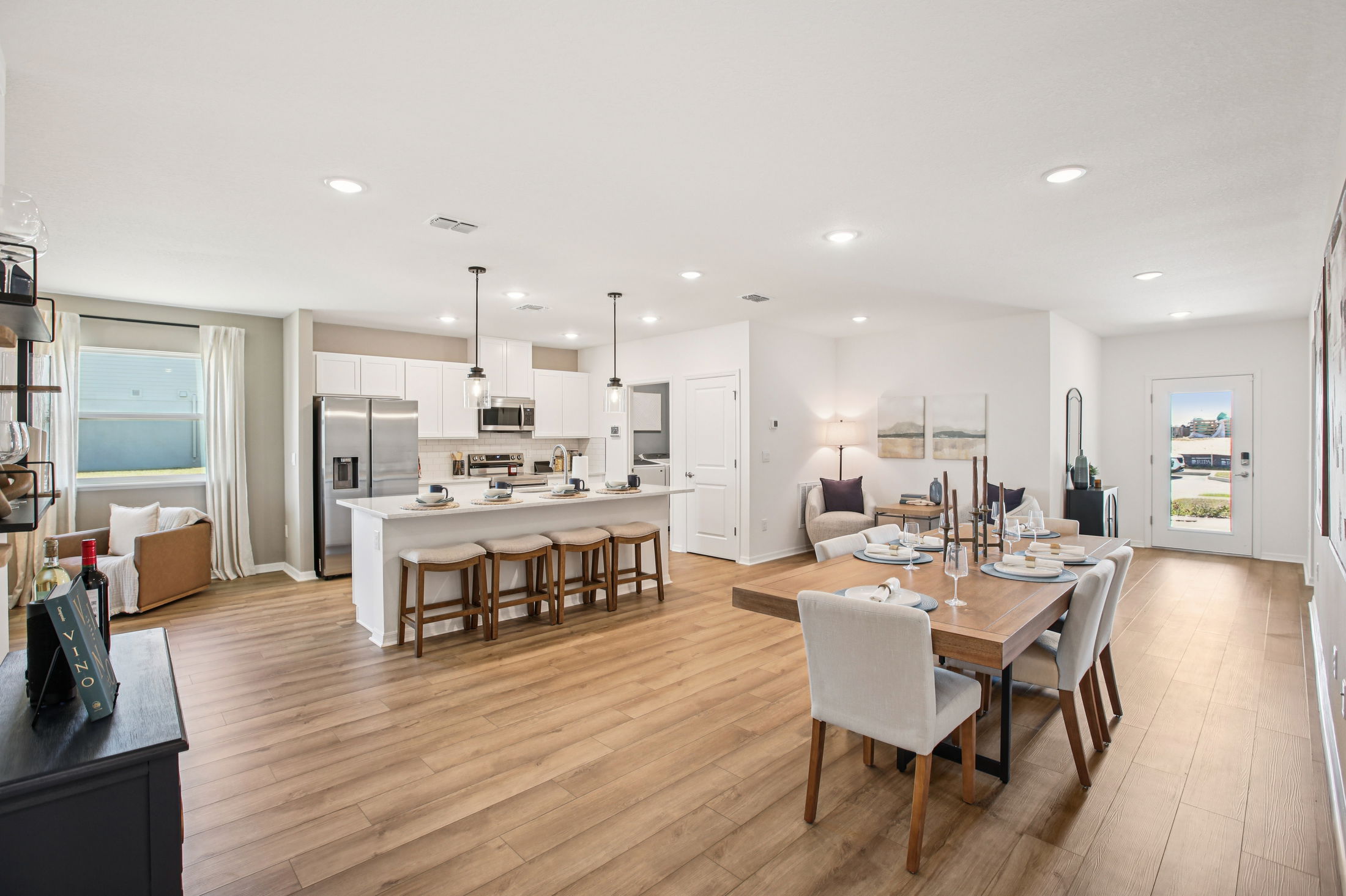 Spacious modern open-concept kitchen and dining area featuring hardwood floors, stainless steel appliances, and stylish decor.