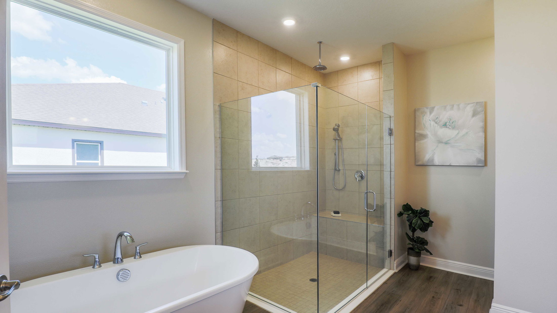 Modern bathroom with a freestanding bathtub, glass-enclosed shower, large window, and elegant decor.