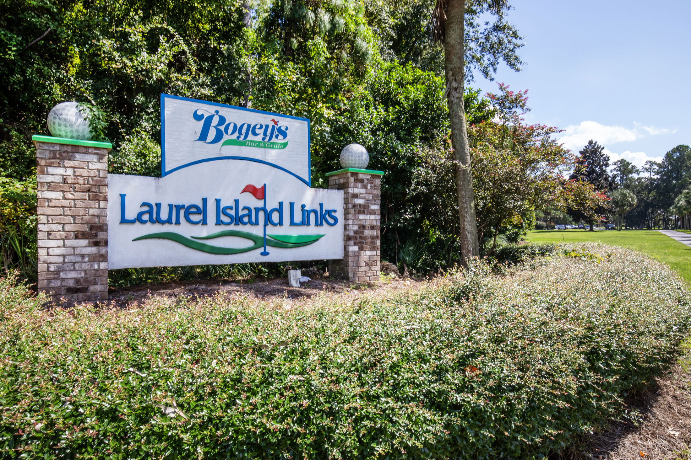 Sign for Laurel Island Links golf course surrounded by lush greenery, featuring a \\\