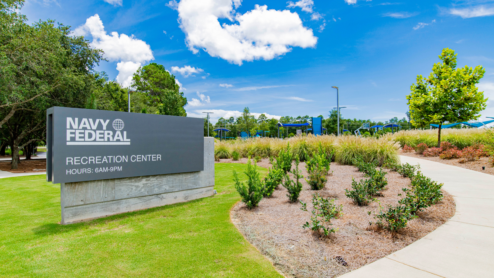 Exterior view of the Navy Federal Recreation Center signage with lush greenery and a clear blue sky backdrop.