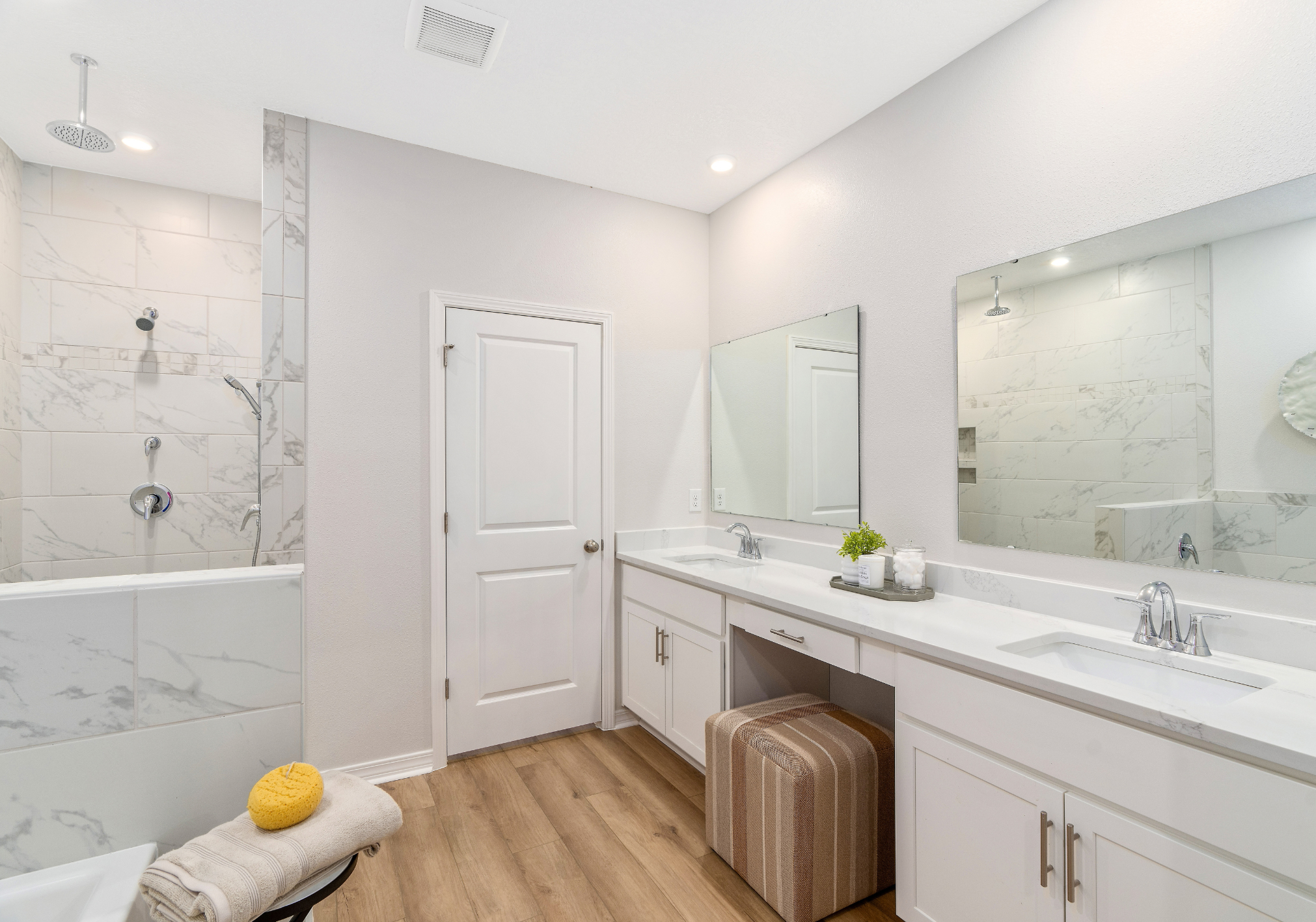 A modern bathroom featuring a double vanity with two sinks, a large mirror, a bathtub, and a shower with marble walls.