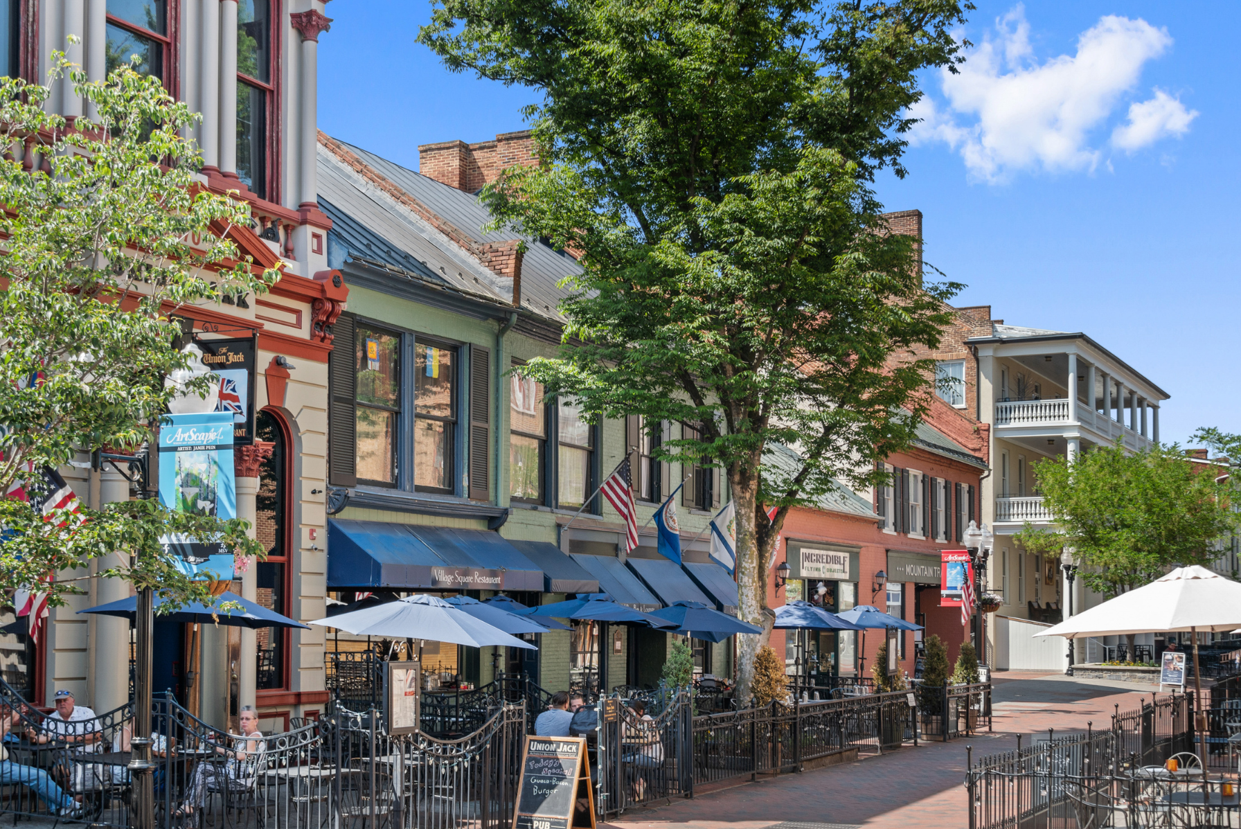 Charming street view of downtown Winchester, Virginia, featuring historic buildings, outdoor dining, and a clear blue sky.