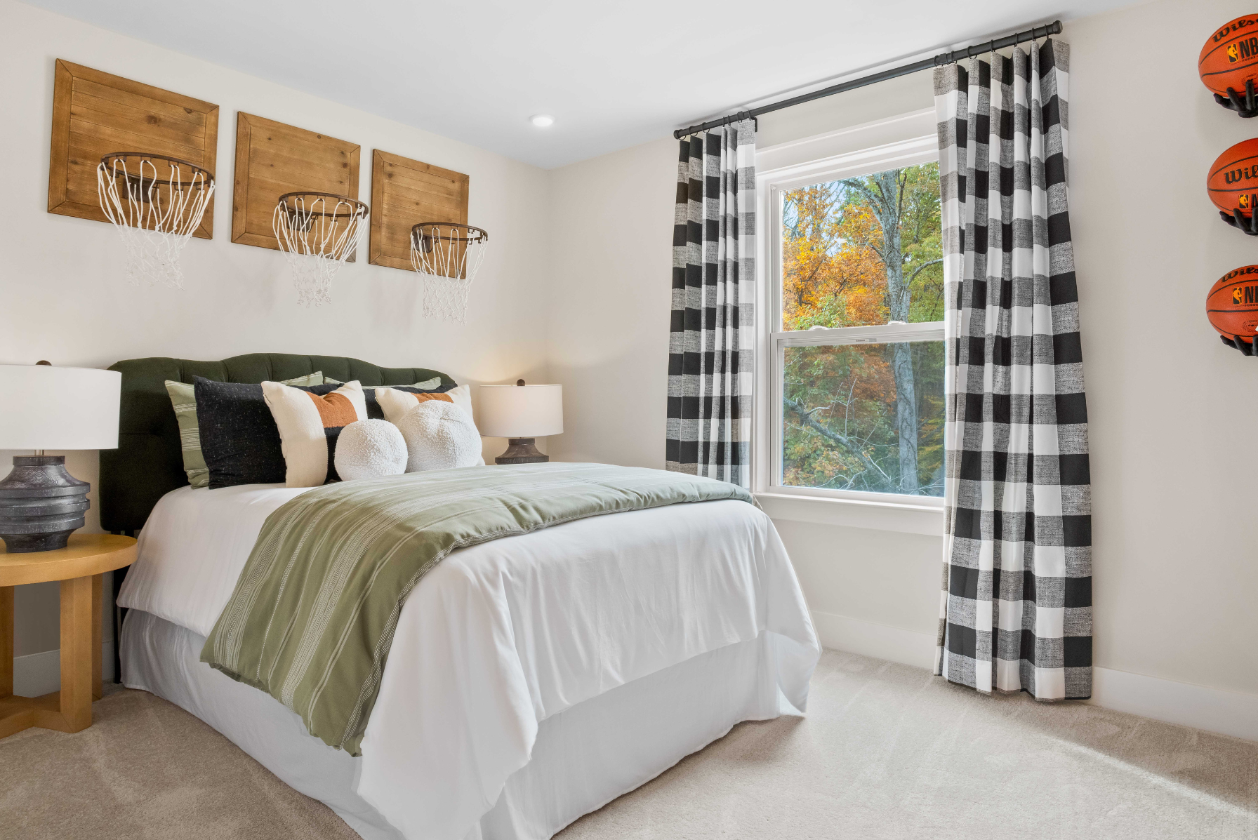 Cozy bedroom with basketball hoops wall decor, checkered curtains, and a window view of autumn trees.