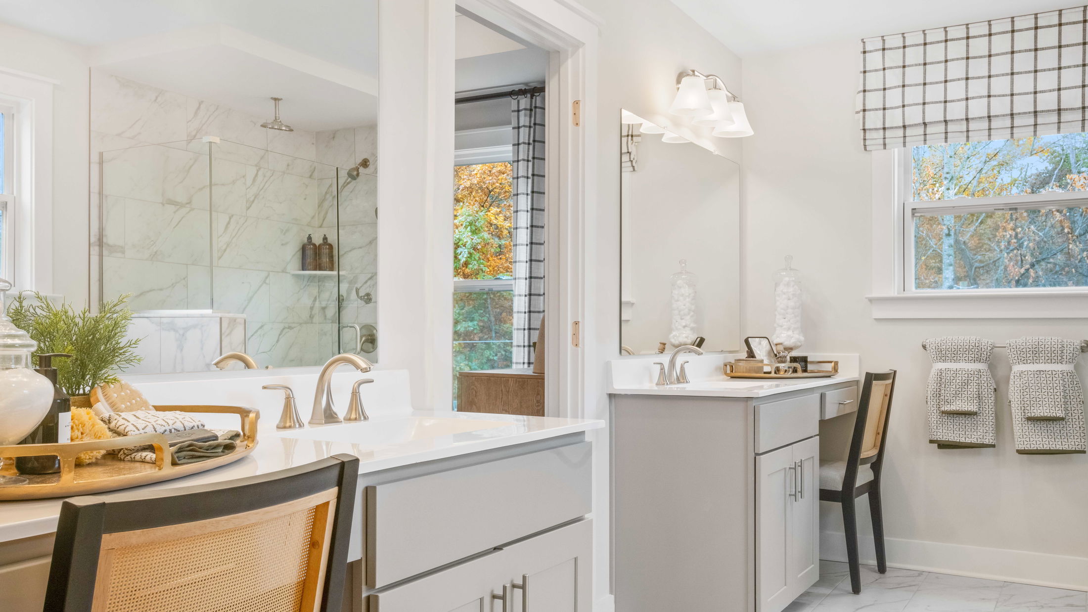 Modern bathroom with double sinks, marble shower, and elegant decor featuring a beige and white color scheme.