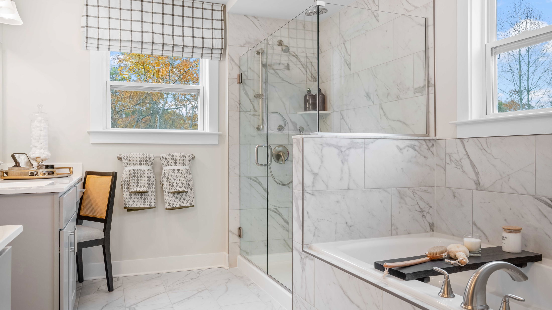 Bright and modern bathroom with large glass shower, marble tiles, and elegant fixtures.