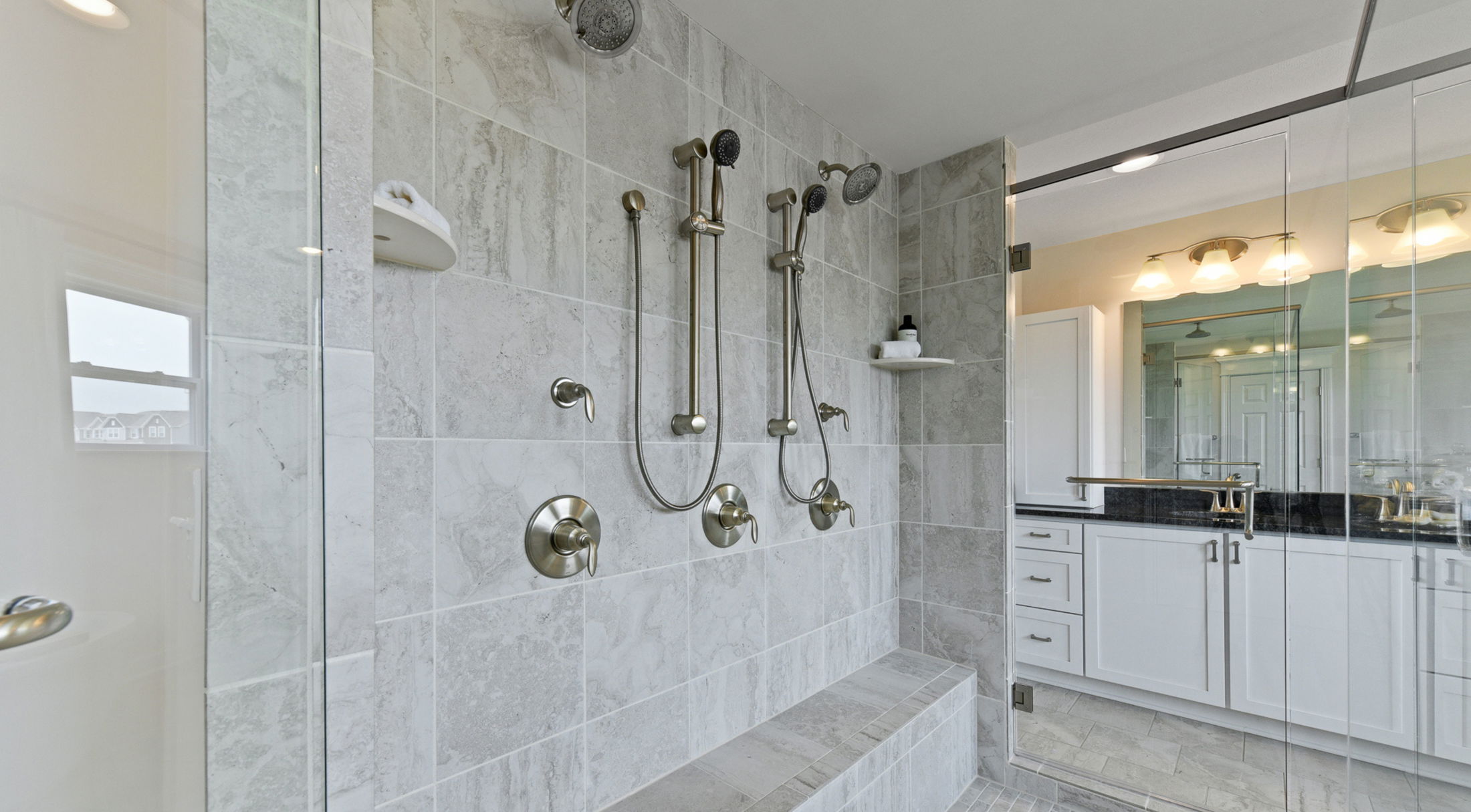 Luxury bathroom featuring a spacious dual shower with elegant stainless steel fixtures and modern white cabinetry.