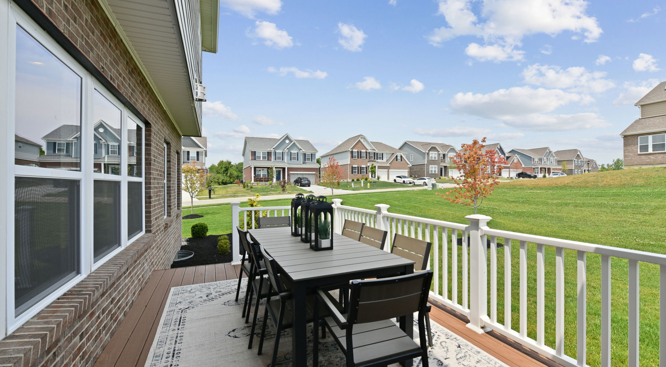 A spacious backyard patio with modern outdoor dining set overlooking a suburban neighborhood.