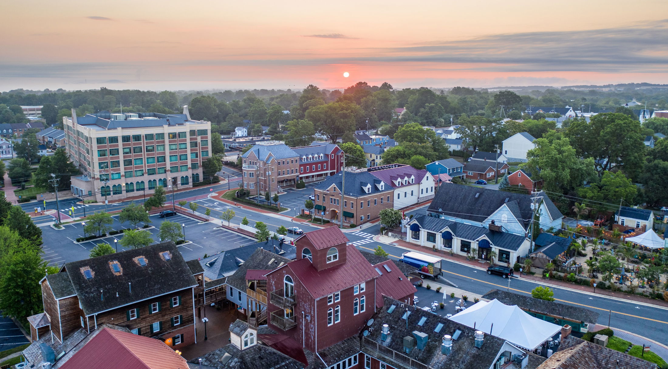 Aerial view of a quaint town with historical buildings and lush greenery at sunrise, highlighting the serene atmosphere of the area.