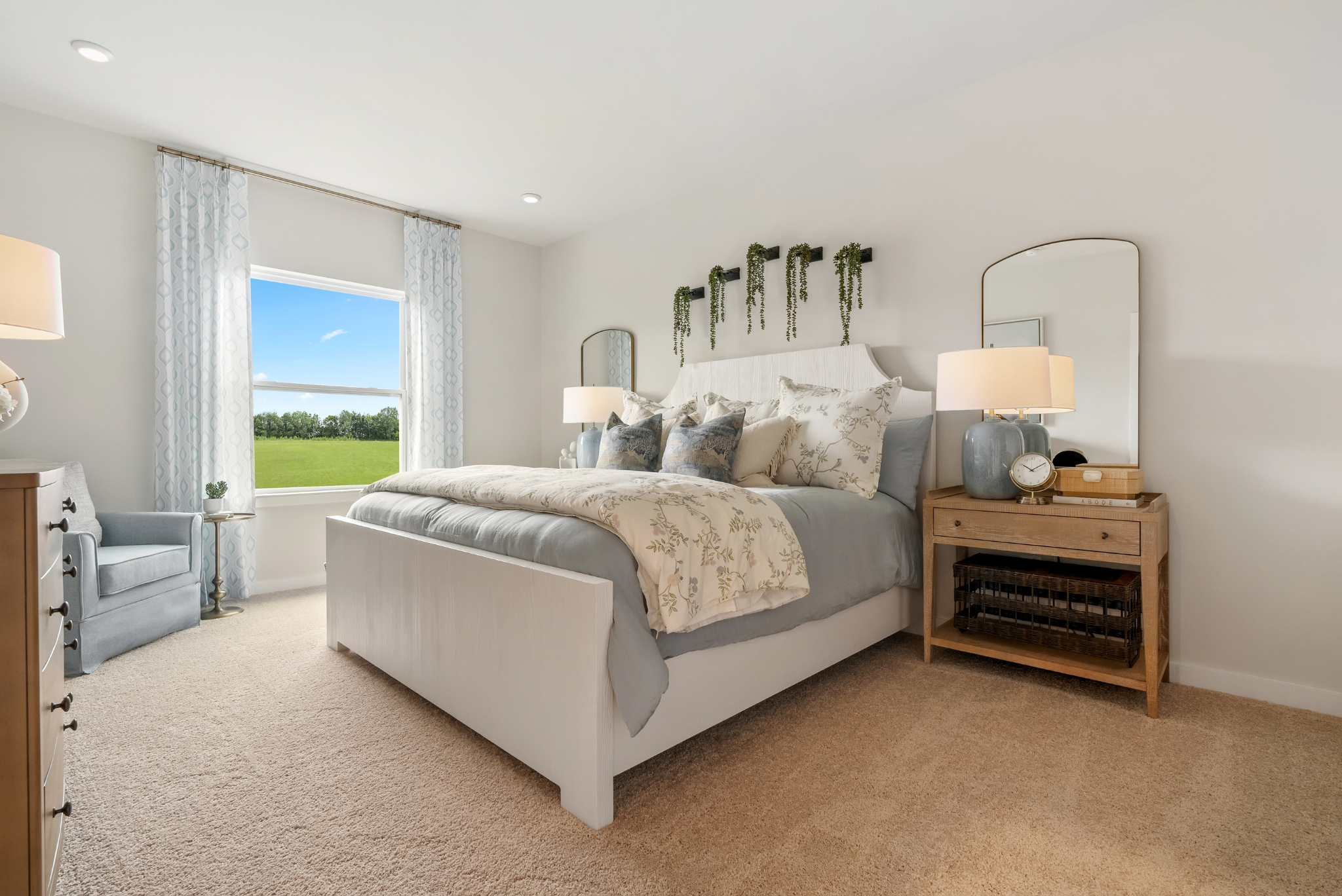 Elegant bedroom interior with a plush bed, light decor, large window, and stylish furniture overlooking a scenic green landscape.