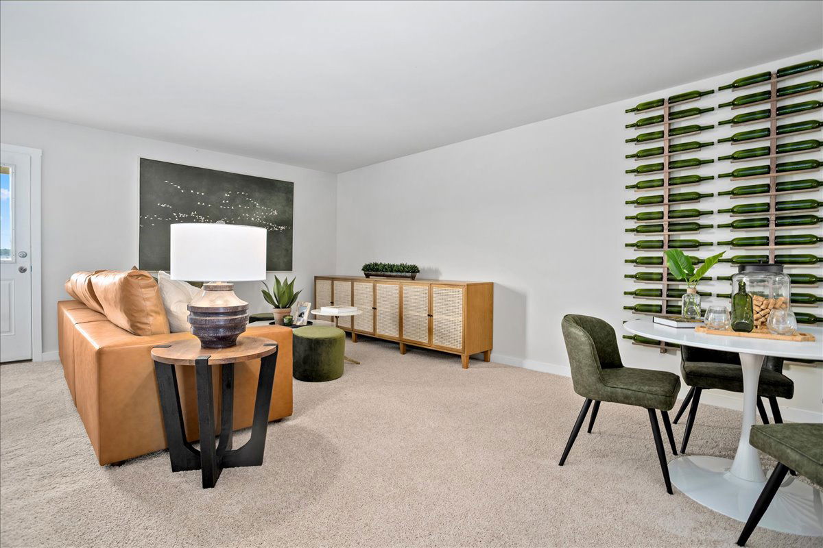 Stylish modern living room with tan leather sofa, unique bottle wall art, and elegant dining area.