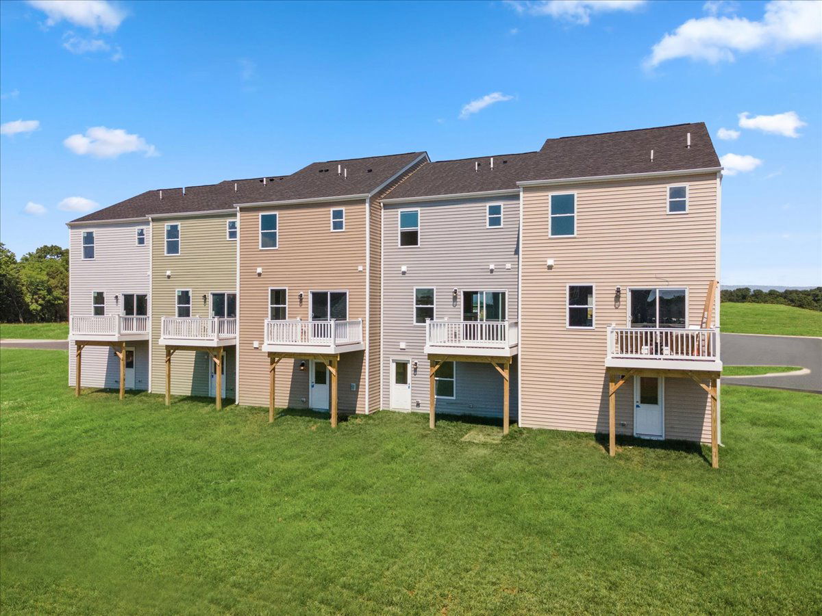 Row of modern townhouses with small balconies set against a clear blue sky.