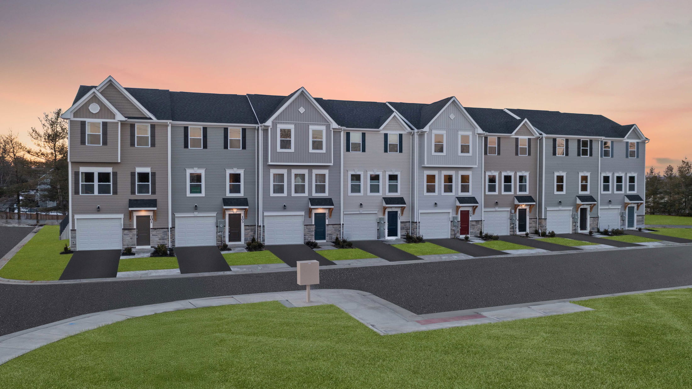 Modern townhouse complex with attached garages at sunset, showcasing a well-maintained residential neighborhood.
