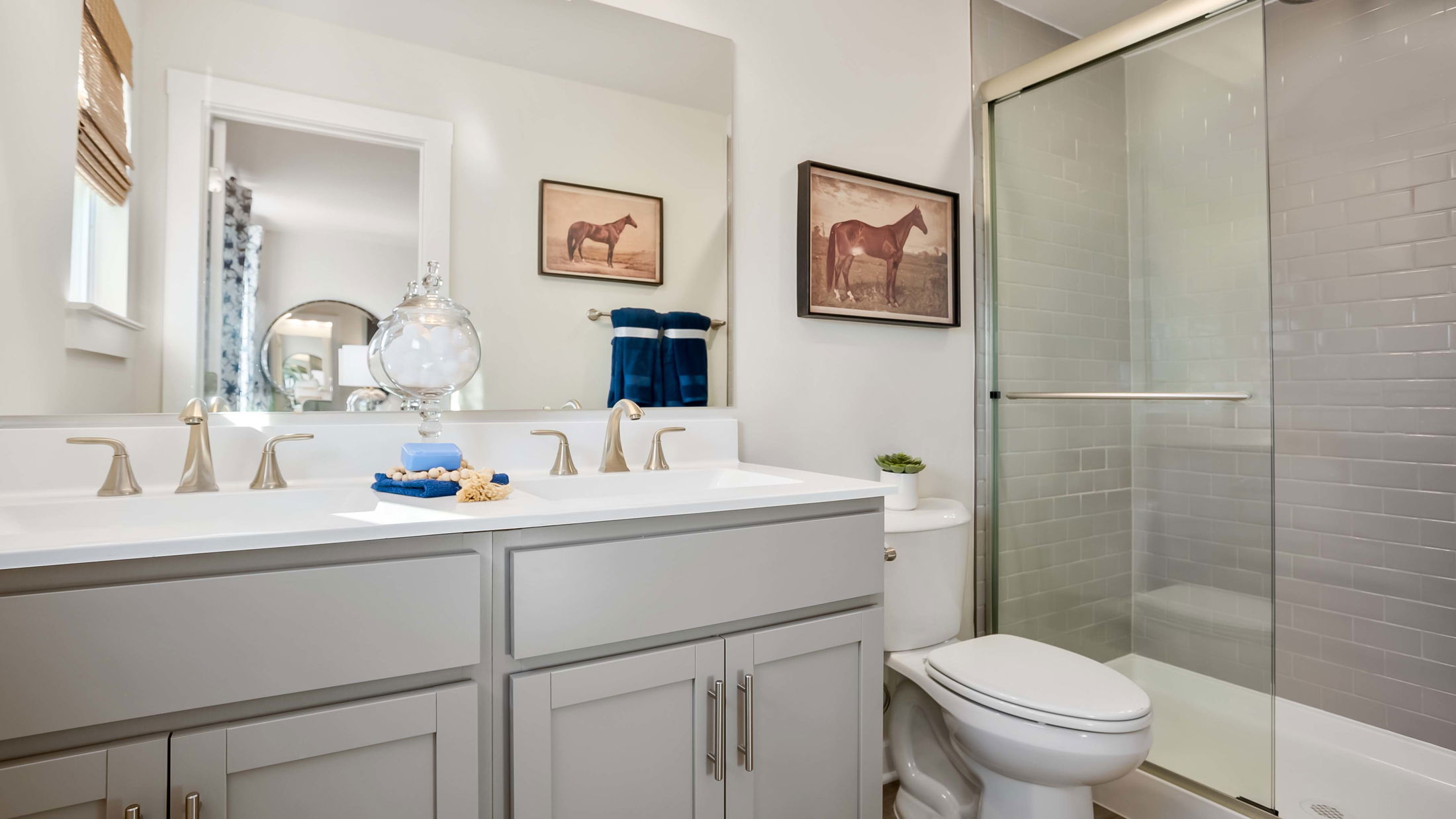 Modern bathroom with a sleek glass shower, dual vanity, and elegant horse-themed wall art.