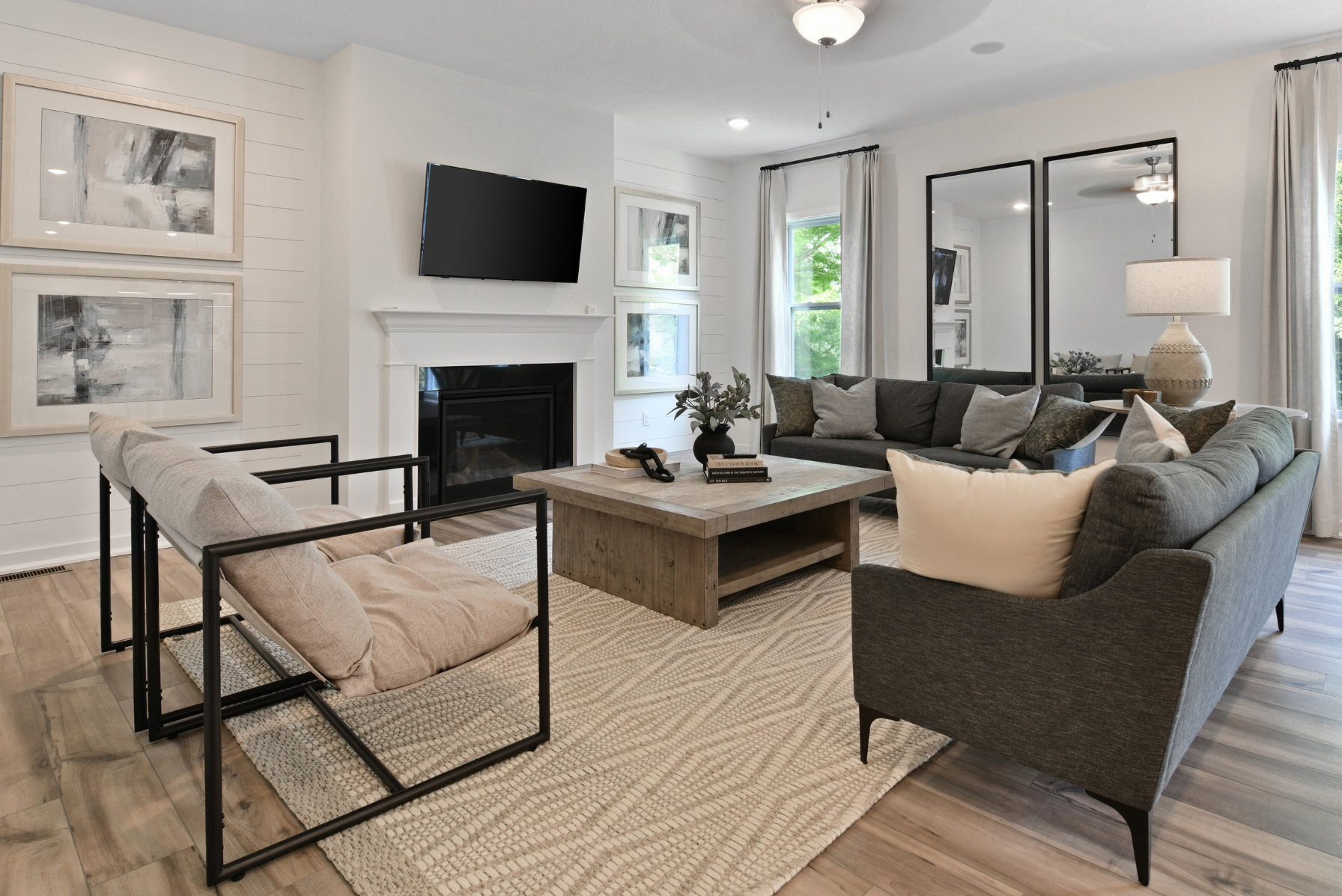 Modern living room with stylish furniture, a cozy fireplace, large windows, and contemporary wall art.