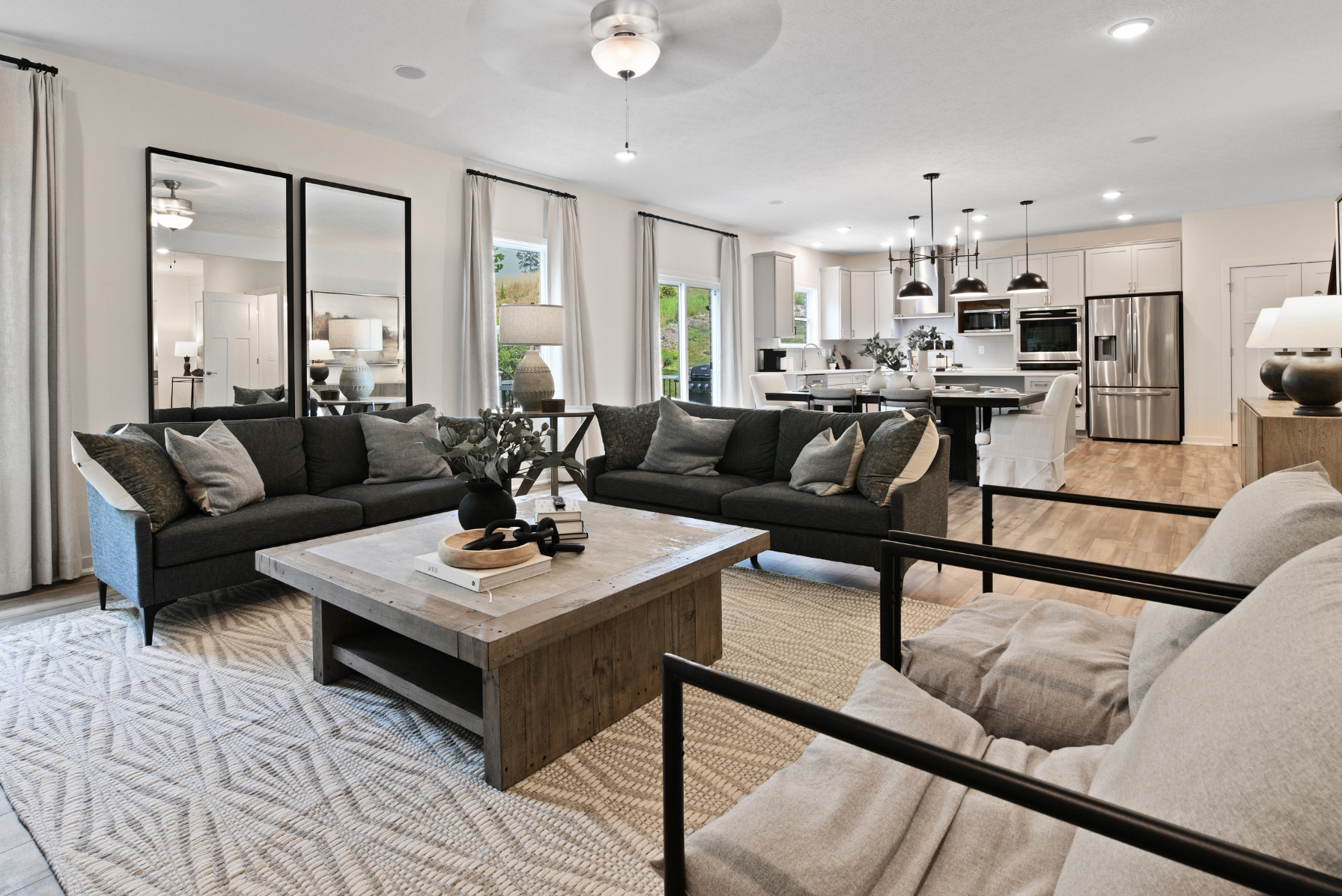 Modern open-concept living room and kitchen with stylish decor, gray sofas, and wooden accents.