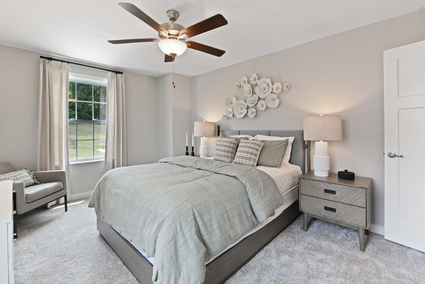 Modern bedroom featuring a comfy bed with mint green bedding, decorative wall art, bedside lamps, and a ceiling fan.