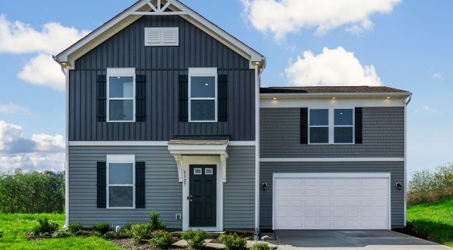 Modern two-story gray house with white garage and lush green lawn on a sunny day.