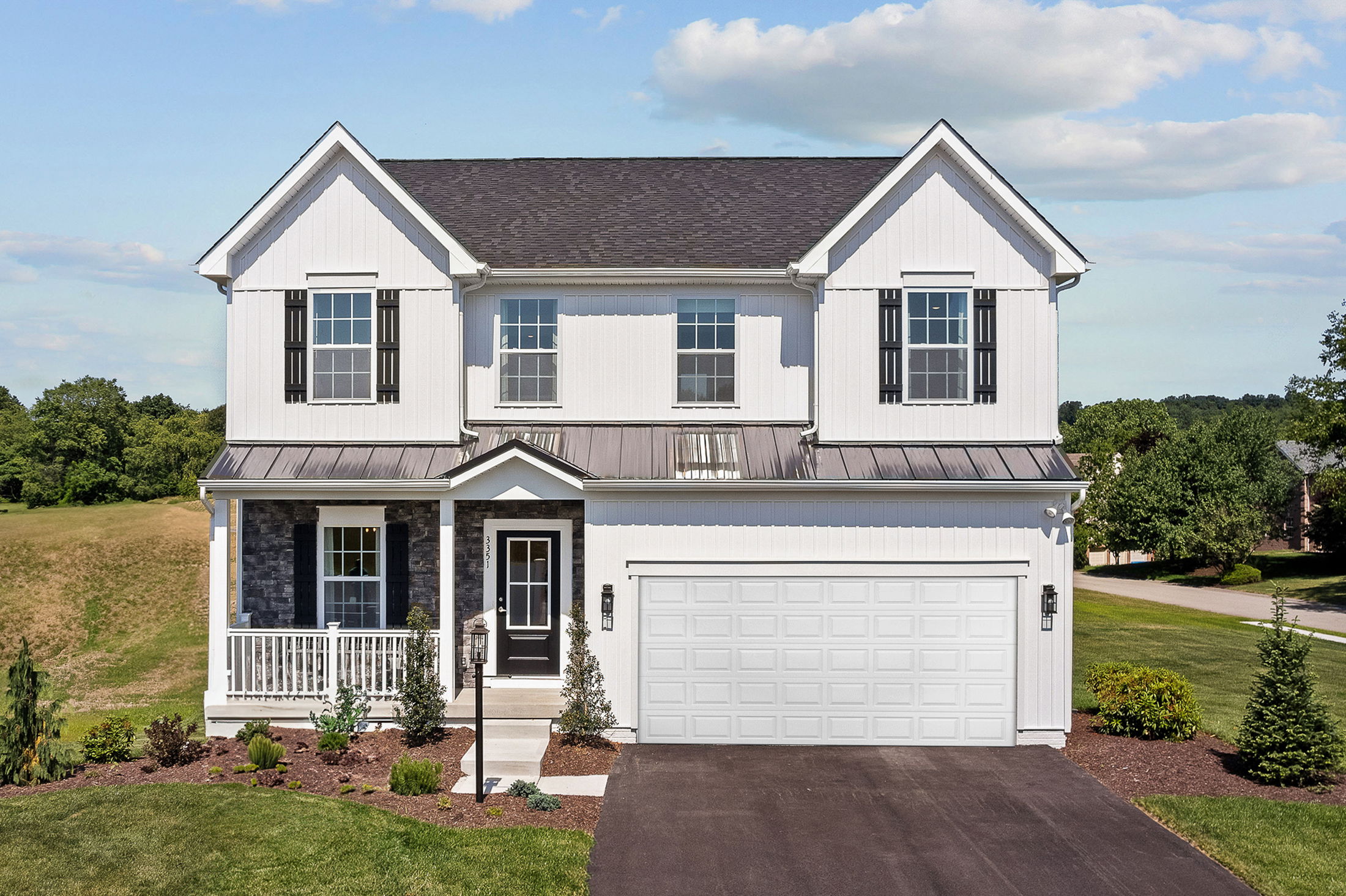 Modern two-story white suburban house with a large garage and manicured lawn under a blue sky.