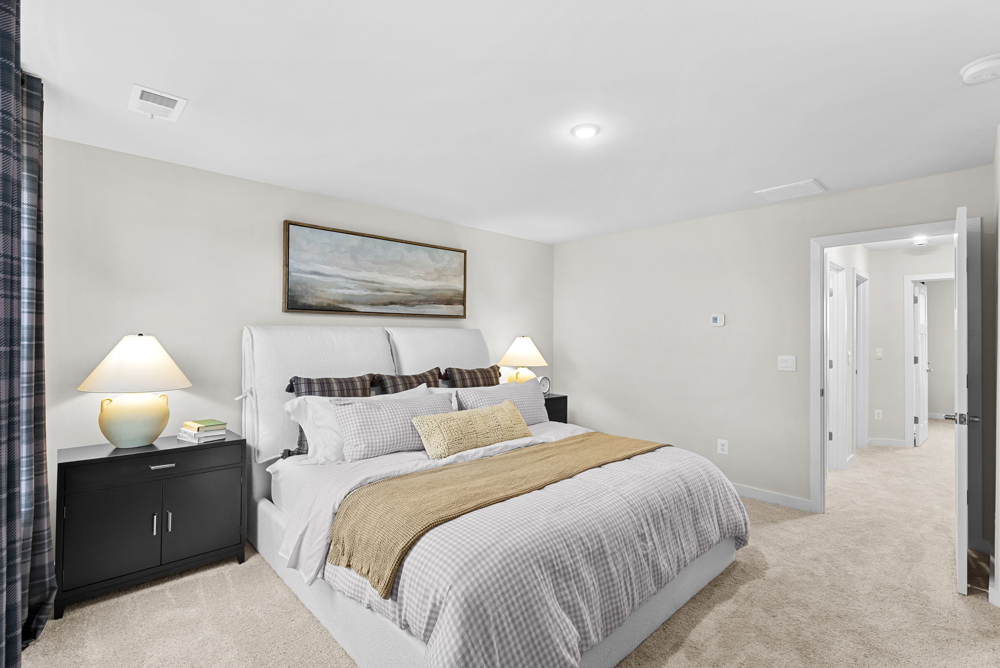 Modern bedroom with a cozy bed, plush bedding, and bedside tables with lamps, showcasing elegant interior design.