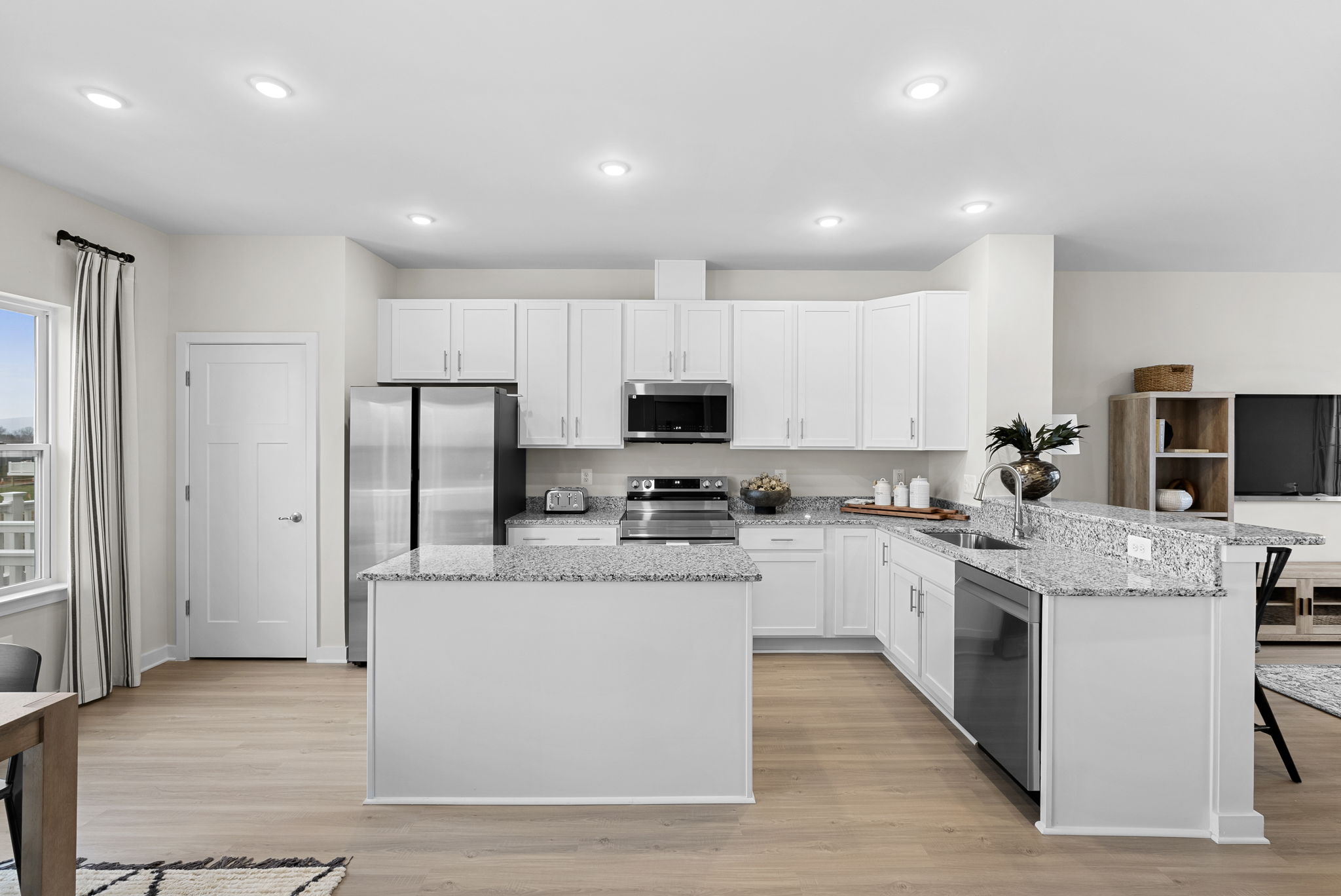 Modern kitchen with white cabinetry, stainless steel appliances, and granite countertops.