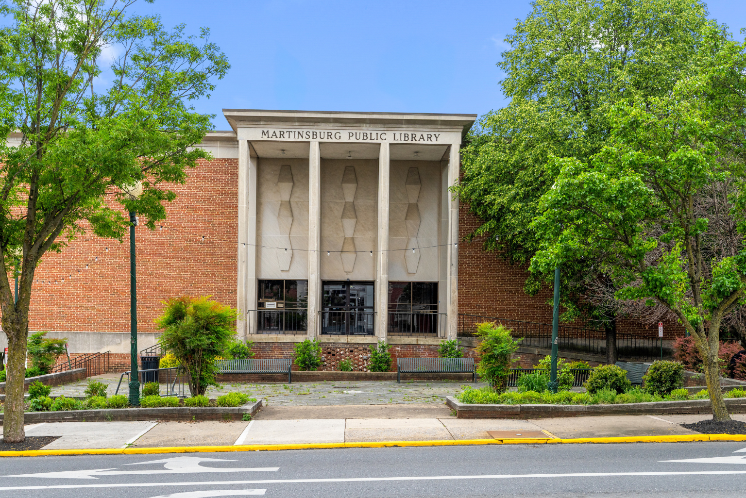 Front exterior view of Martinsburg Public Library, surrounded by trees and greenery.