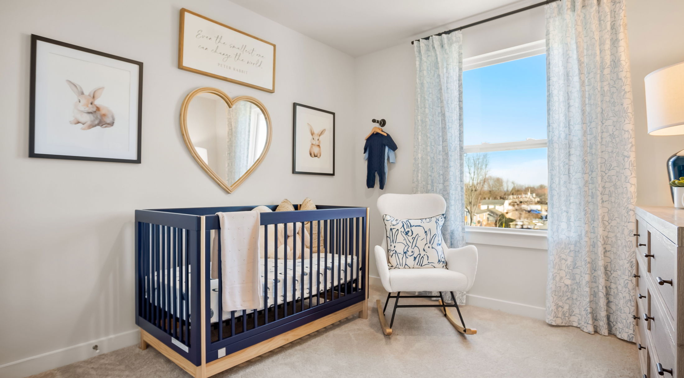 Modern baby nursery with a navy crib, heart-shaped mirror, and elegant decor.