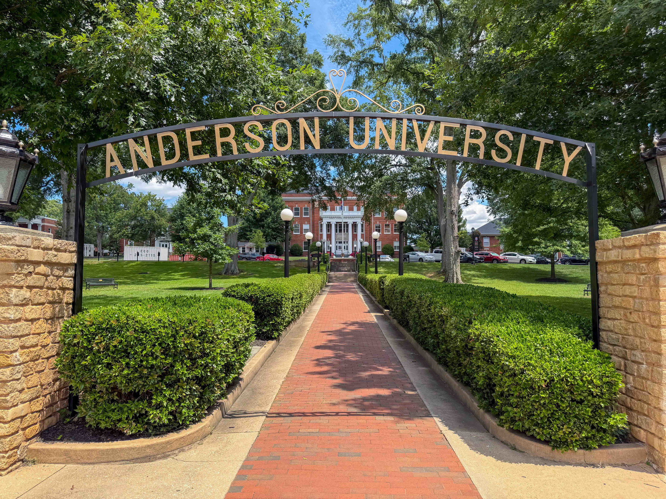 Entrance to Anderson University with a brick pathway and lush greenery.