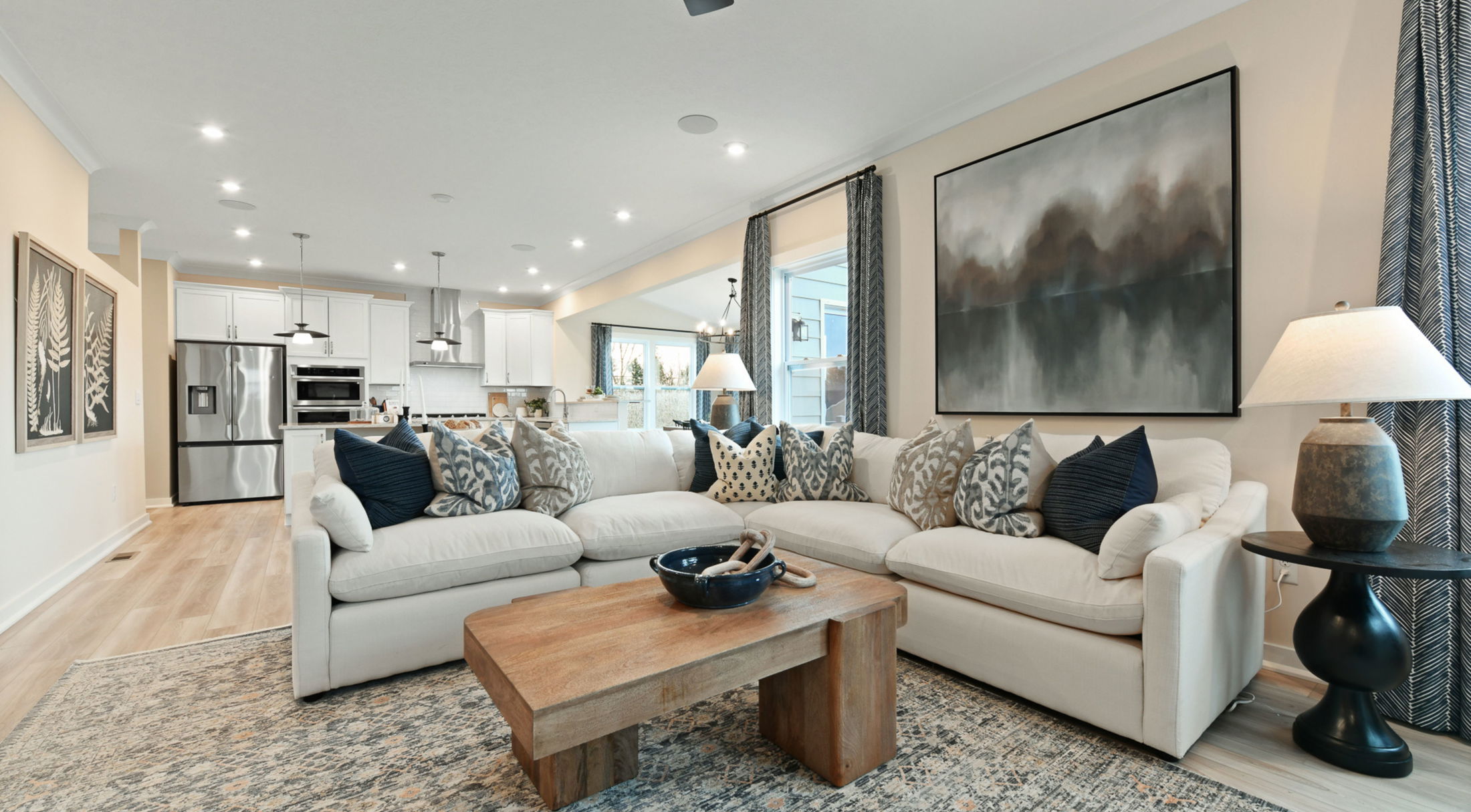 Modern open-concept living room with a cozy beige sofa, wooden coffee table, and stylish kitchen in the background.