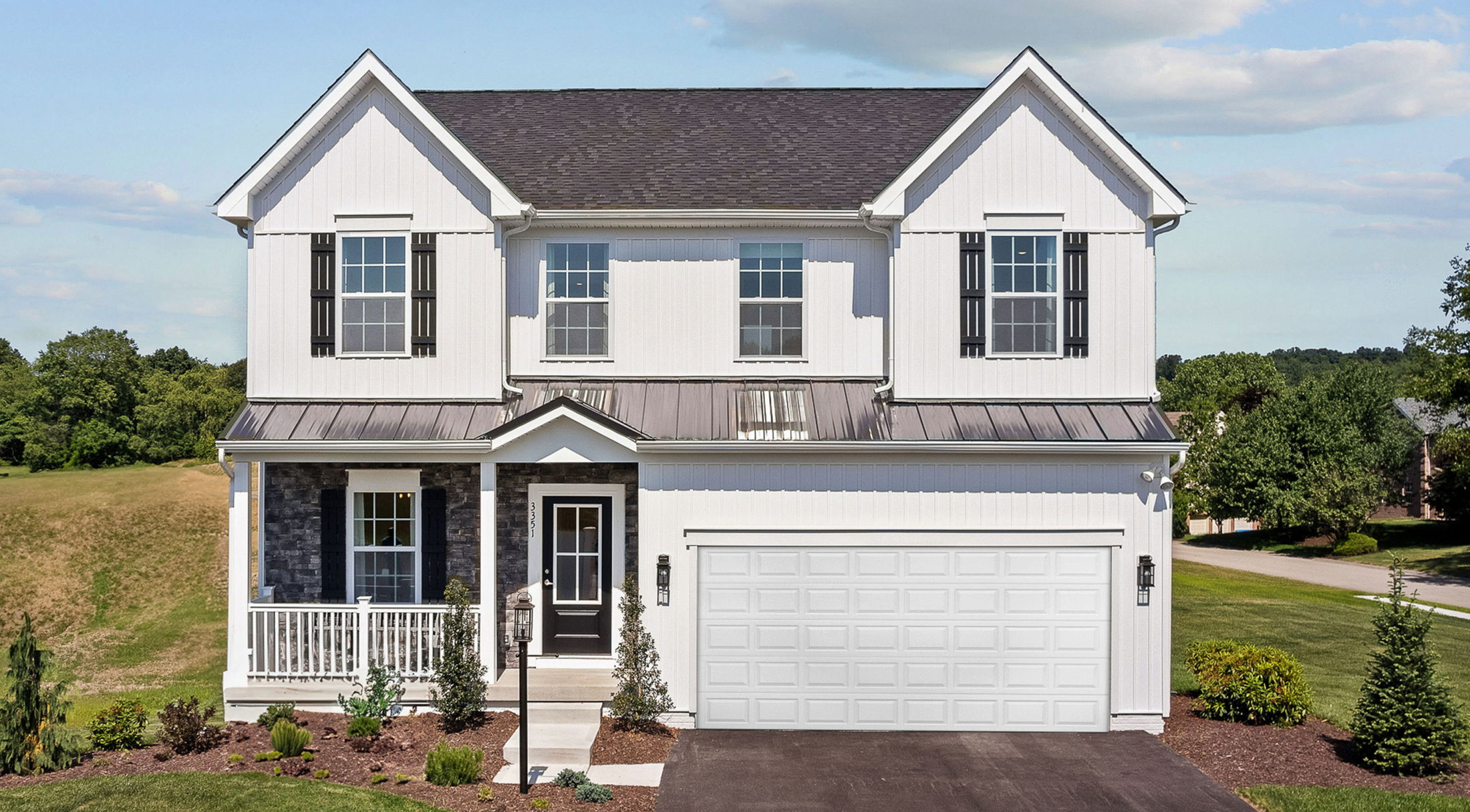 Two-story white suburban house with black shutters, a garage, and a manicured lawn.