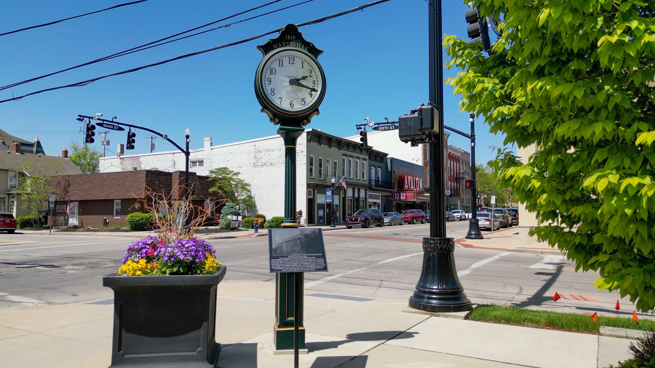 Street clock and colorful flowers at a historic intersection in downtown Marysville, Ohio on a sunny day.