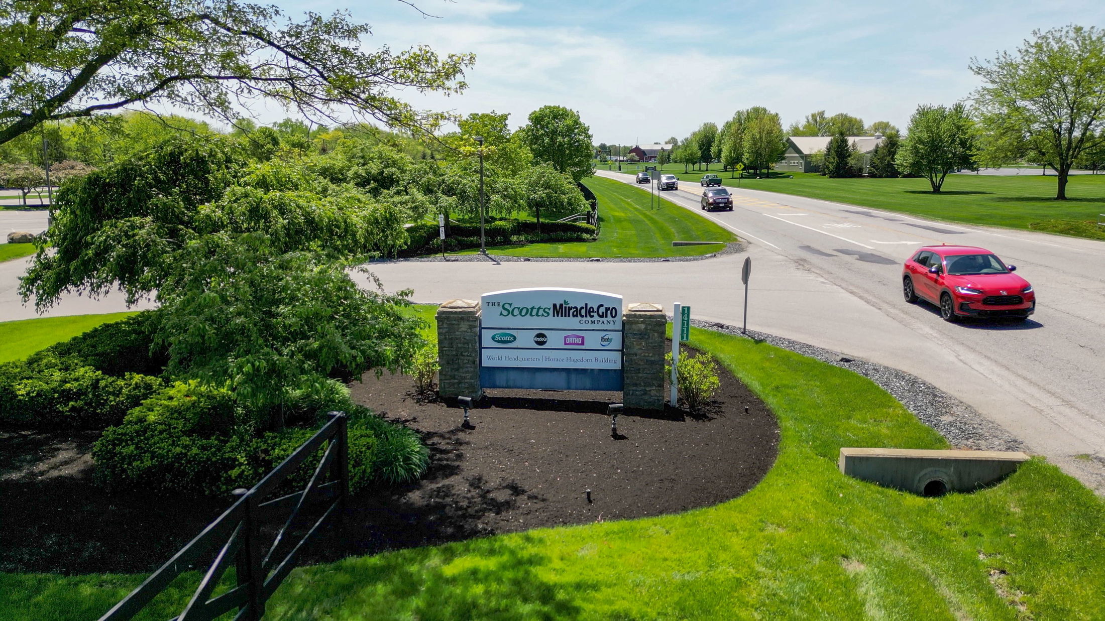 Entrance sign for The Scotts Miracle-Gro Company World Headquarters surrounded by lush greenery along a suburban road.