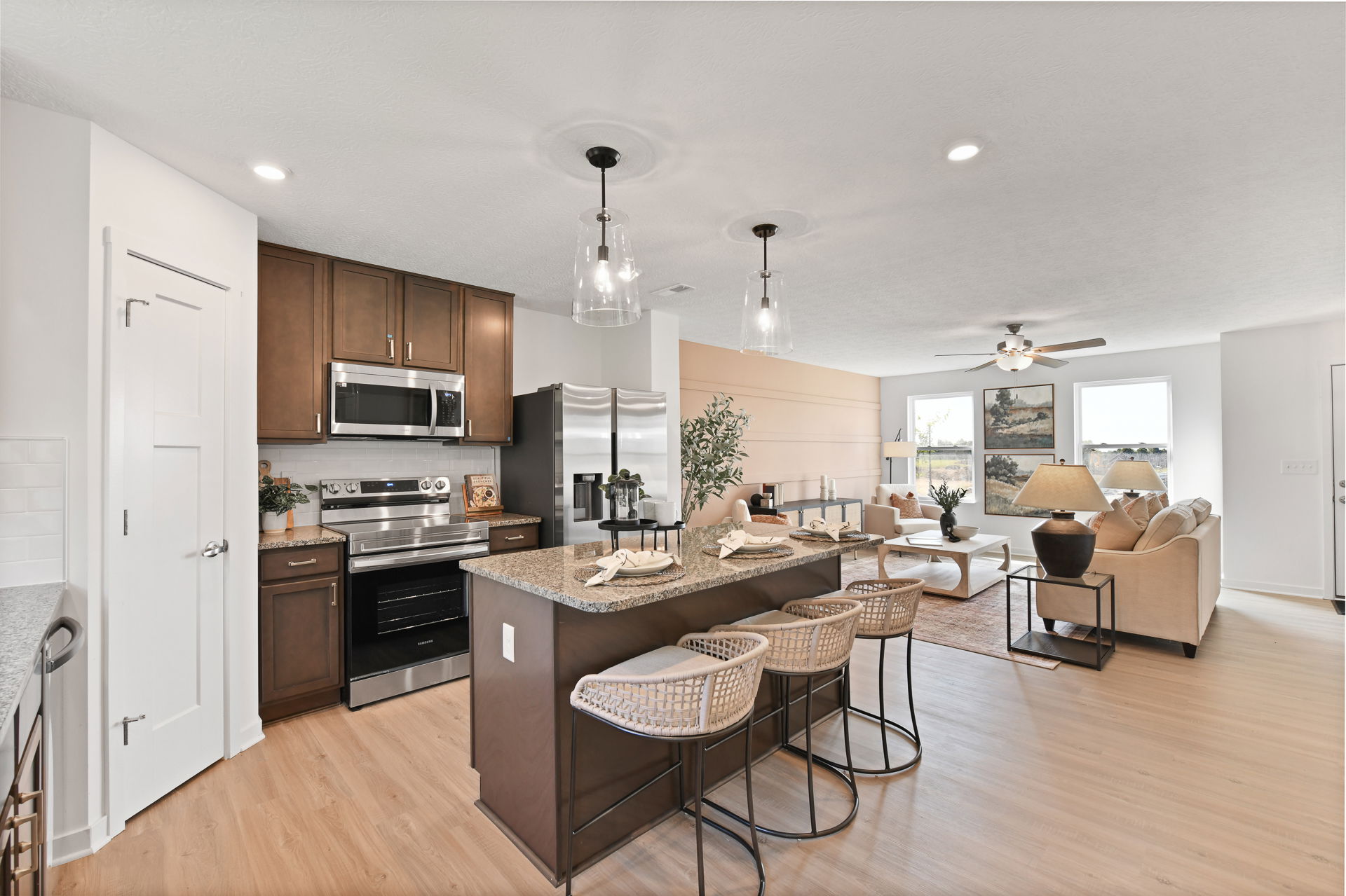 Modern open-concept kitchen and living room with island seating, stainless steel appliances, and cozy neutral decor.