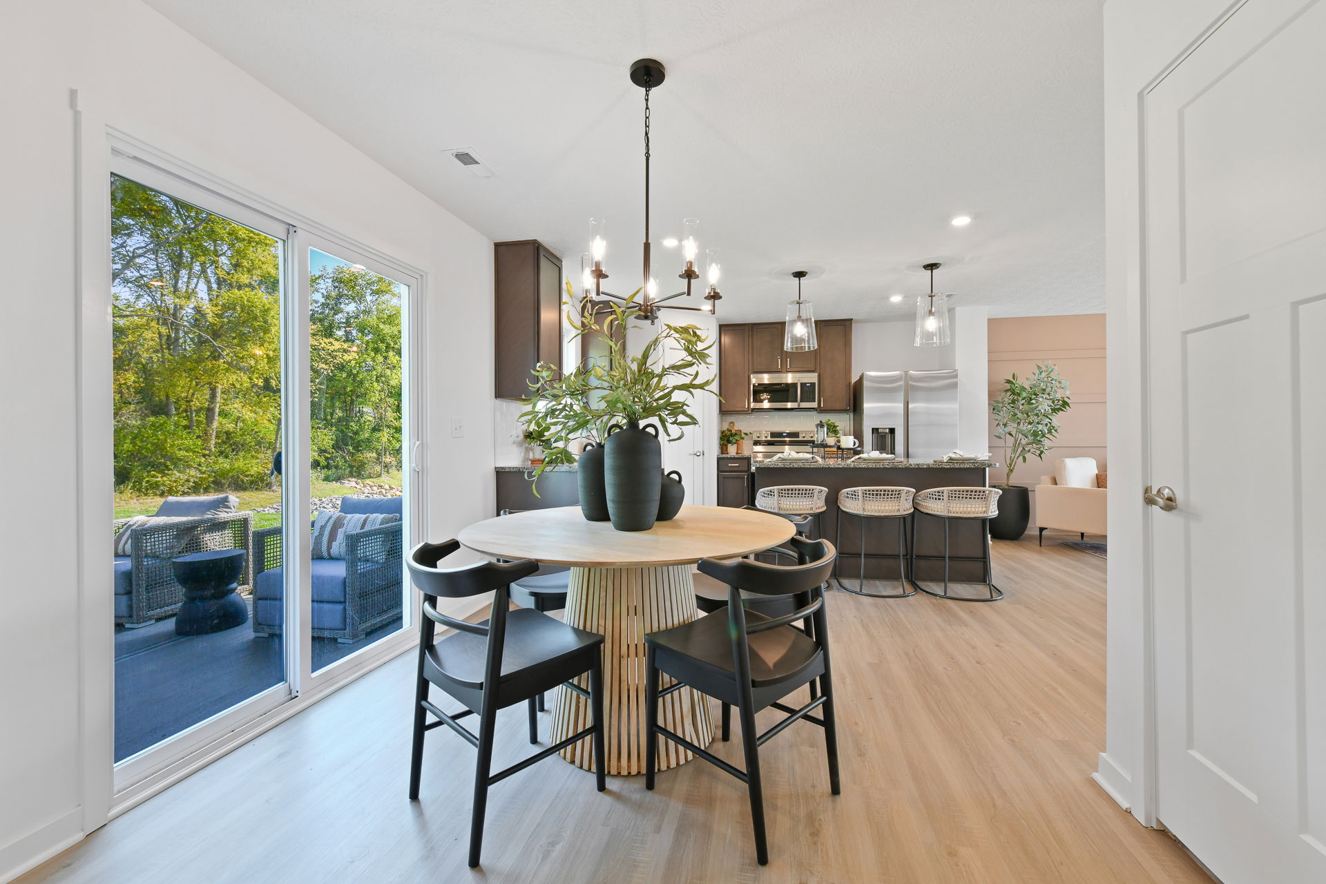 Modern open-concept kitchen and dining area with sliding glass doors overlooking a lush backyard.
