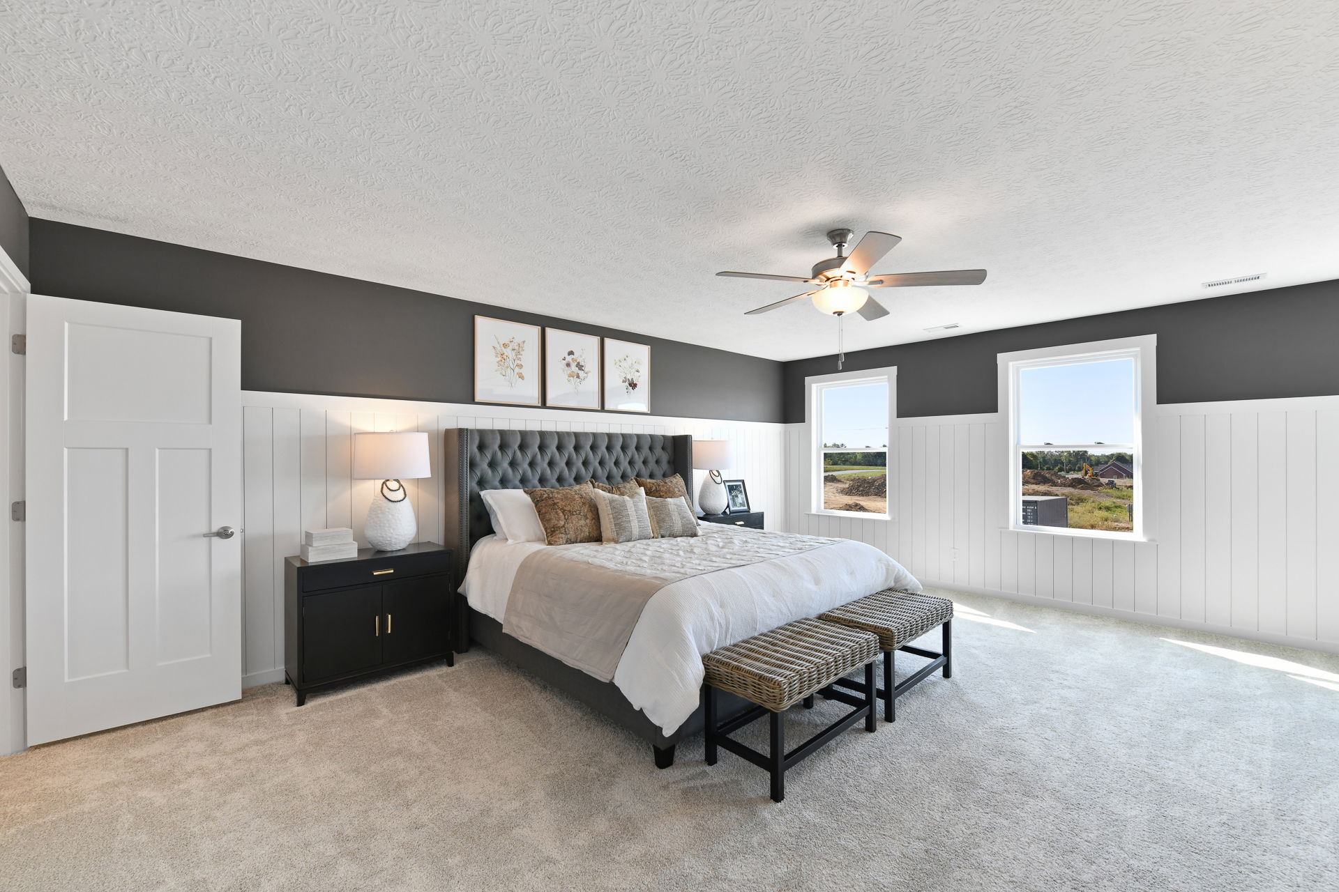Elegant bedroom featuring a luxurious bed with tufted headboard, stylish nightstands, modern ceiling fan, and scenic outdoor view.